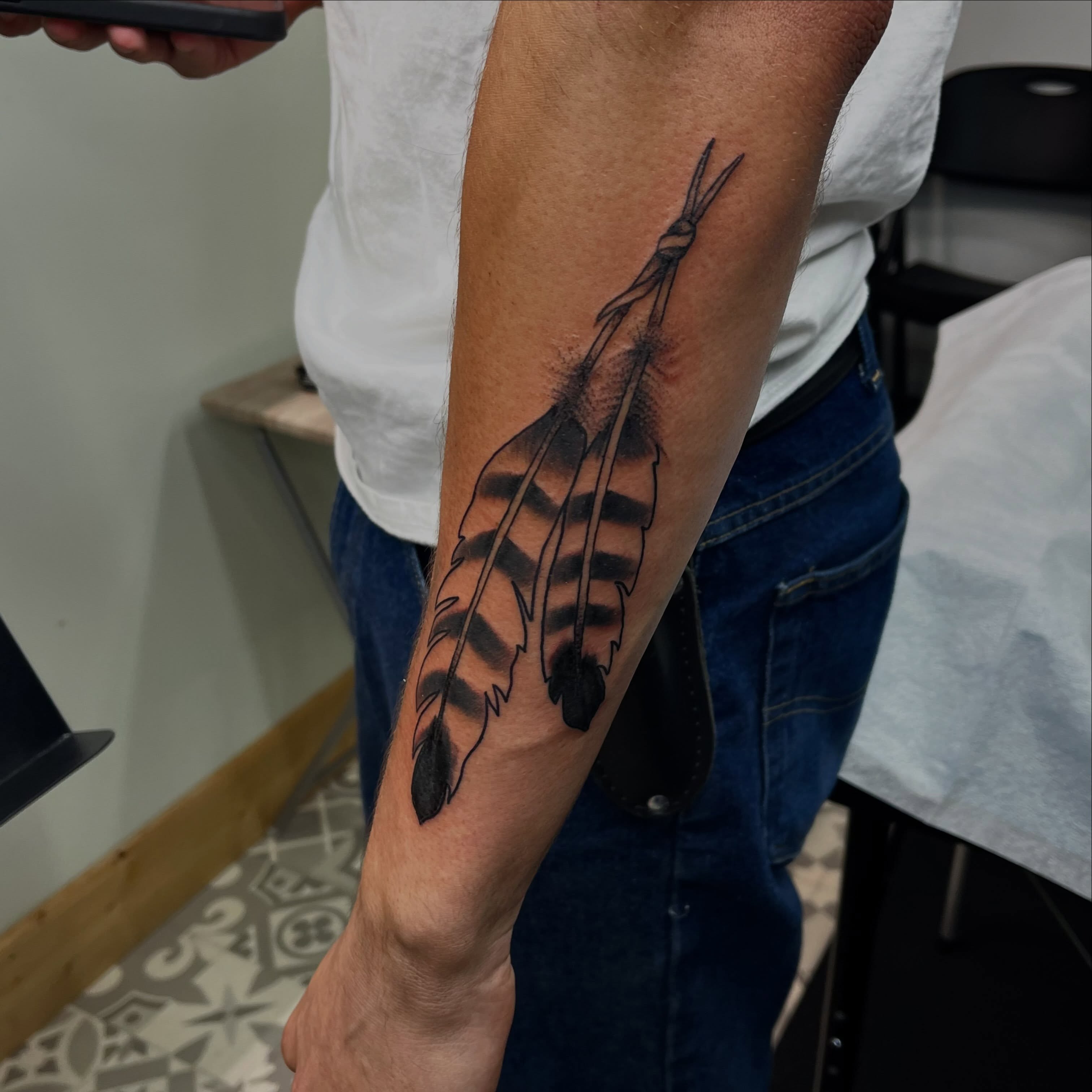 Feather black and grey tattoo on the forearm by Mason McCubbin