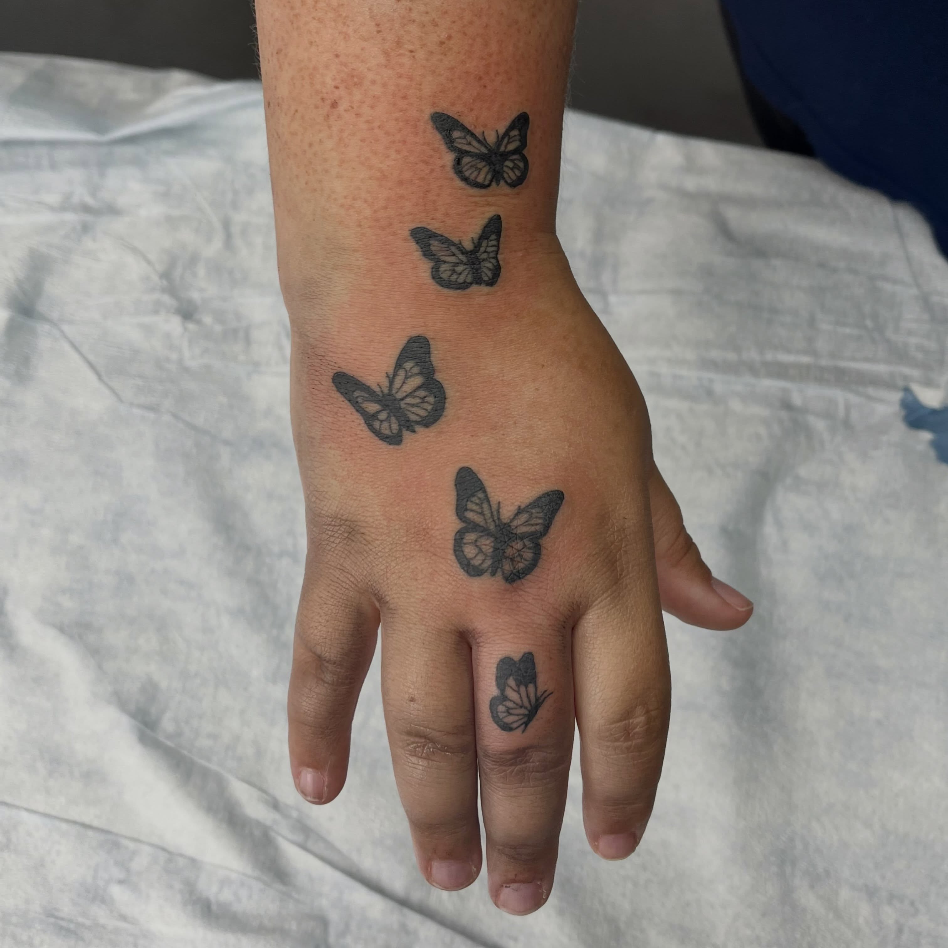 Butterflies black and grey tattoo on the hand by Mason McCubbin
