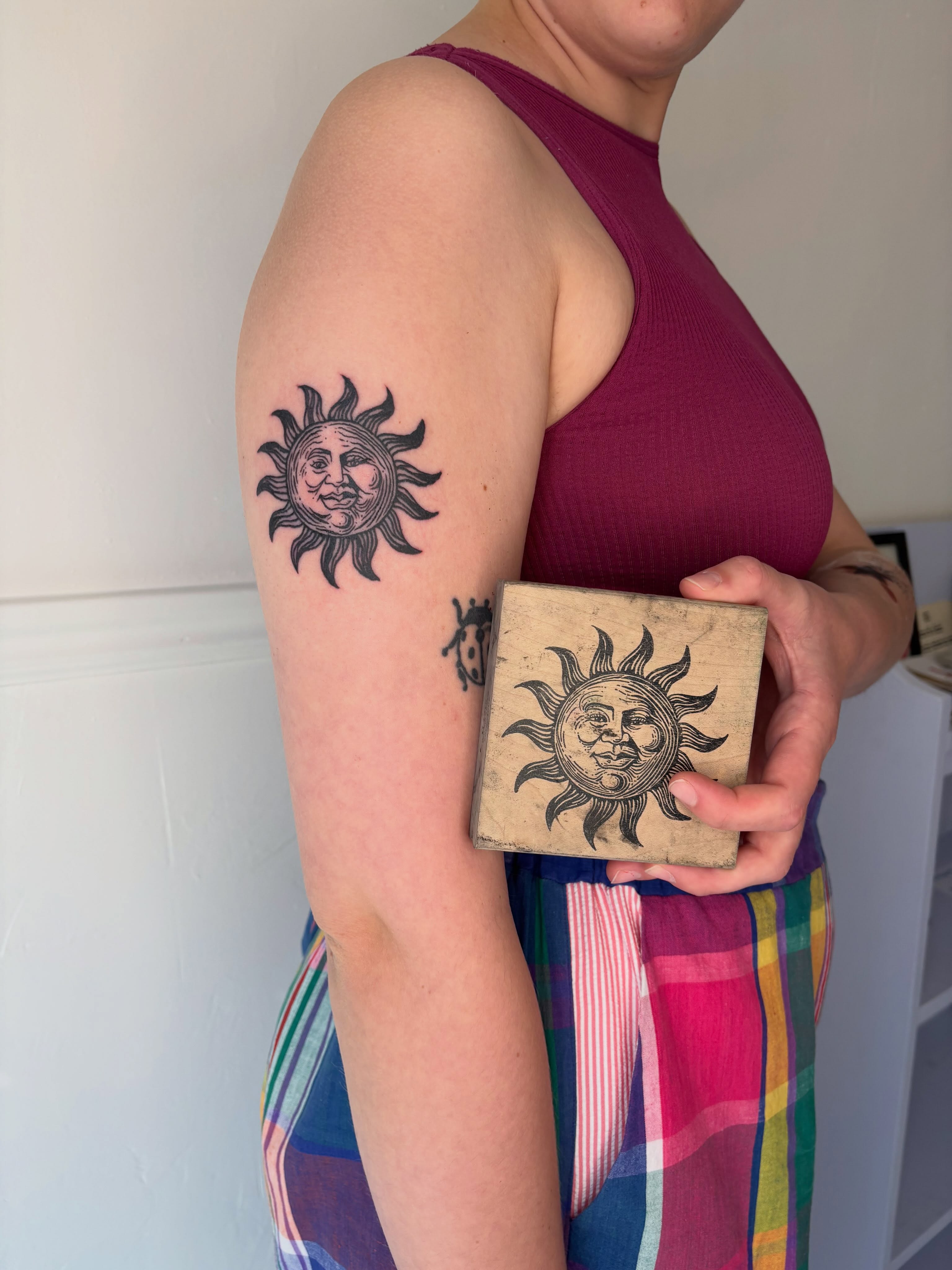 Sun American traditional tattoo on the upper arm by Topher Belmont