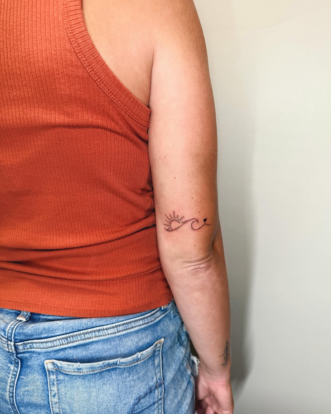 Sun and wave fine line tattoo on the forearm by Ashlee Burkey