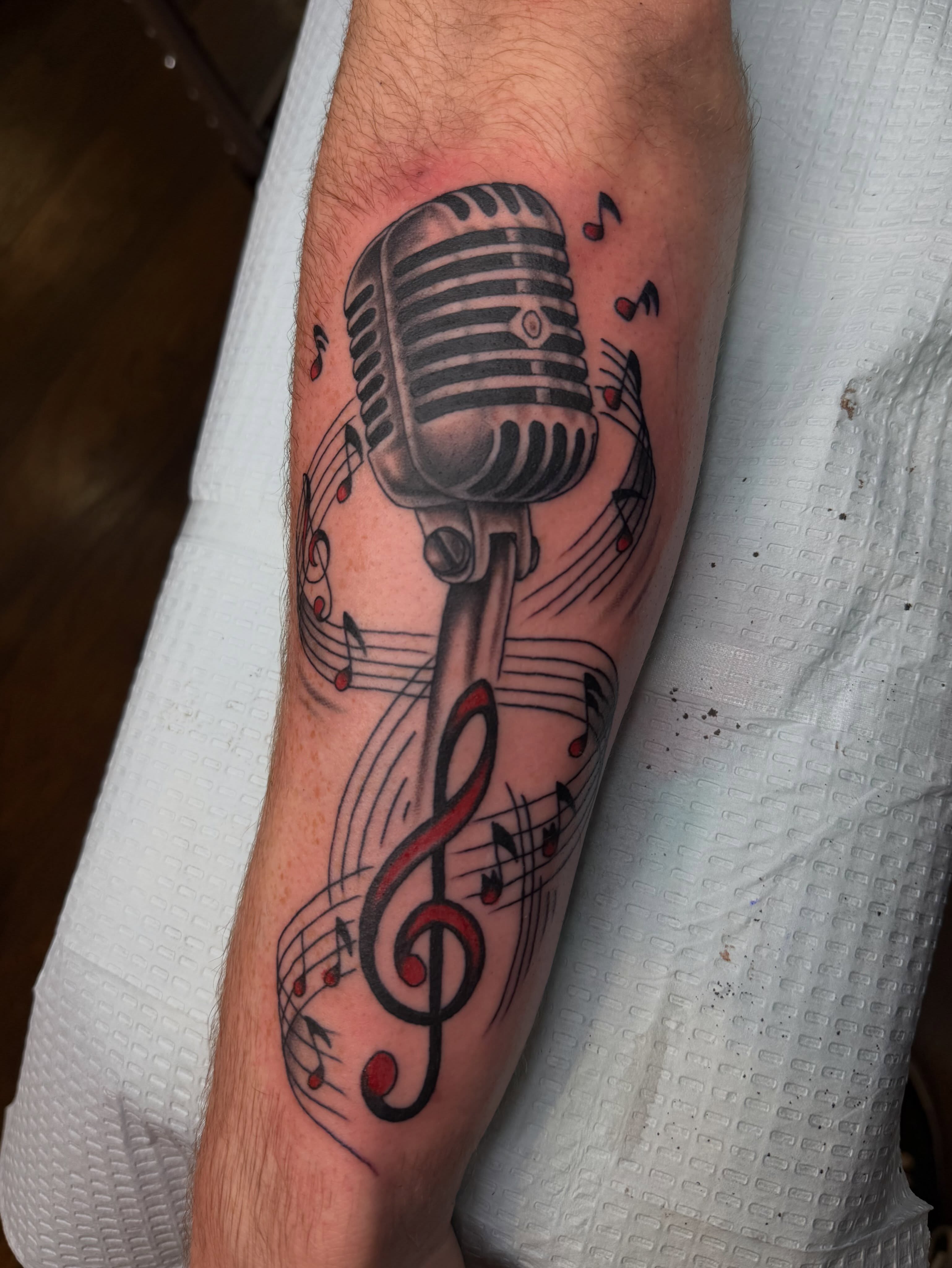 Microphone and music notes American traditional tattoo on the forearm by Thomas Cook