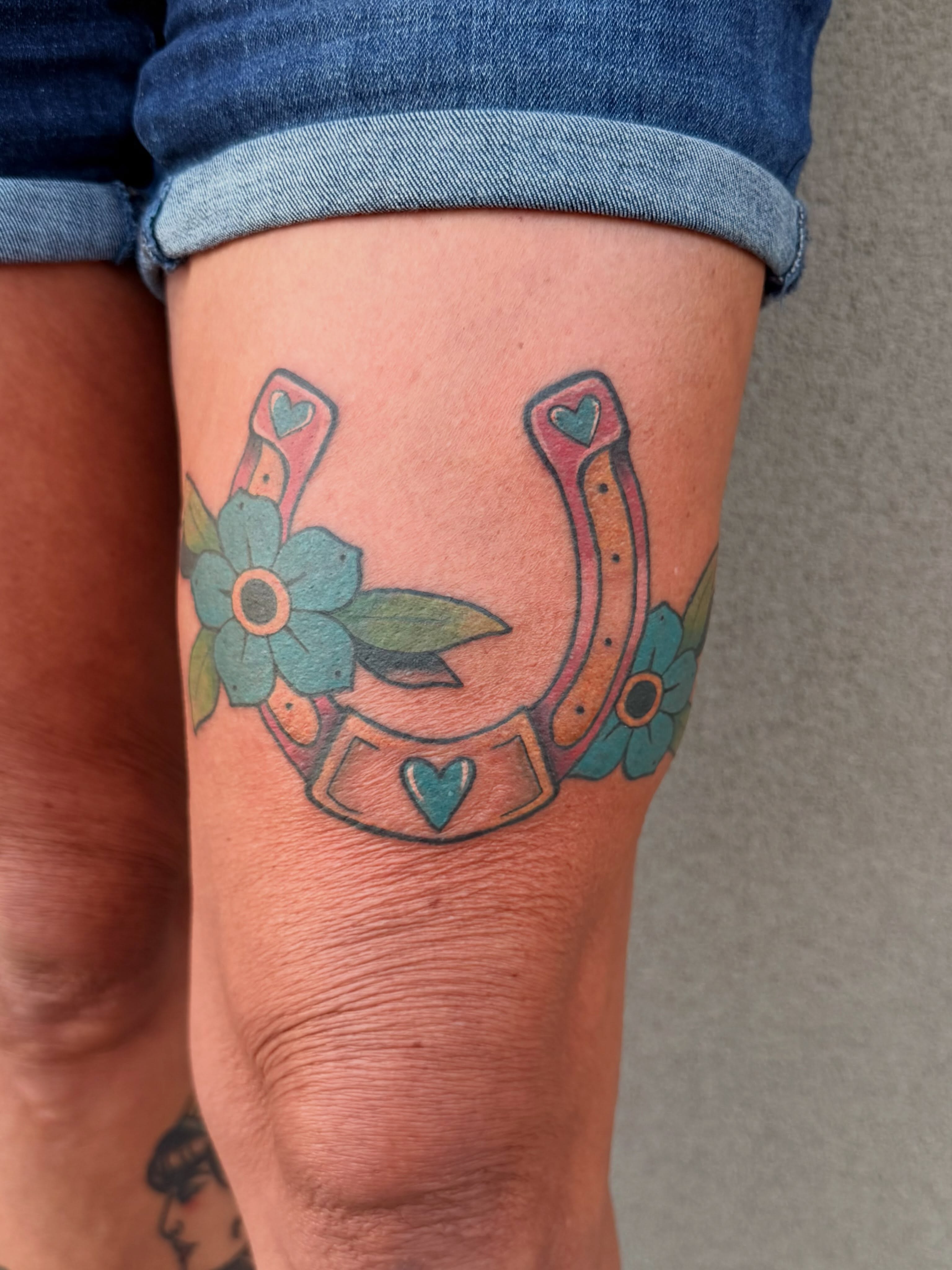Horseshoe and flowers American traditional tattoo on the thigh by Ellari