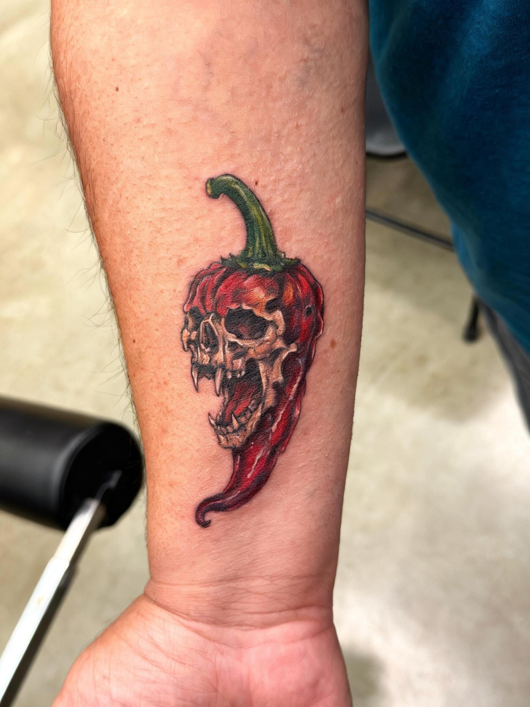 Chili pepper skull realism tattoo on the forearm by Gisette Gomez