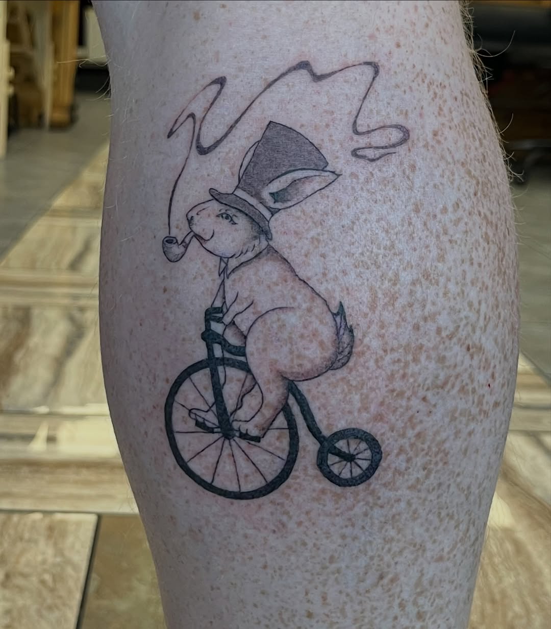 Rabbit on a bicycle fine line tattoo on the calf by Hayes