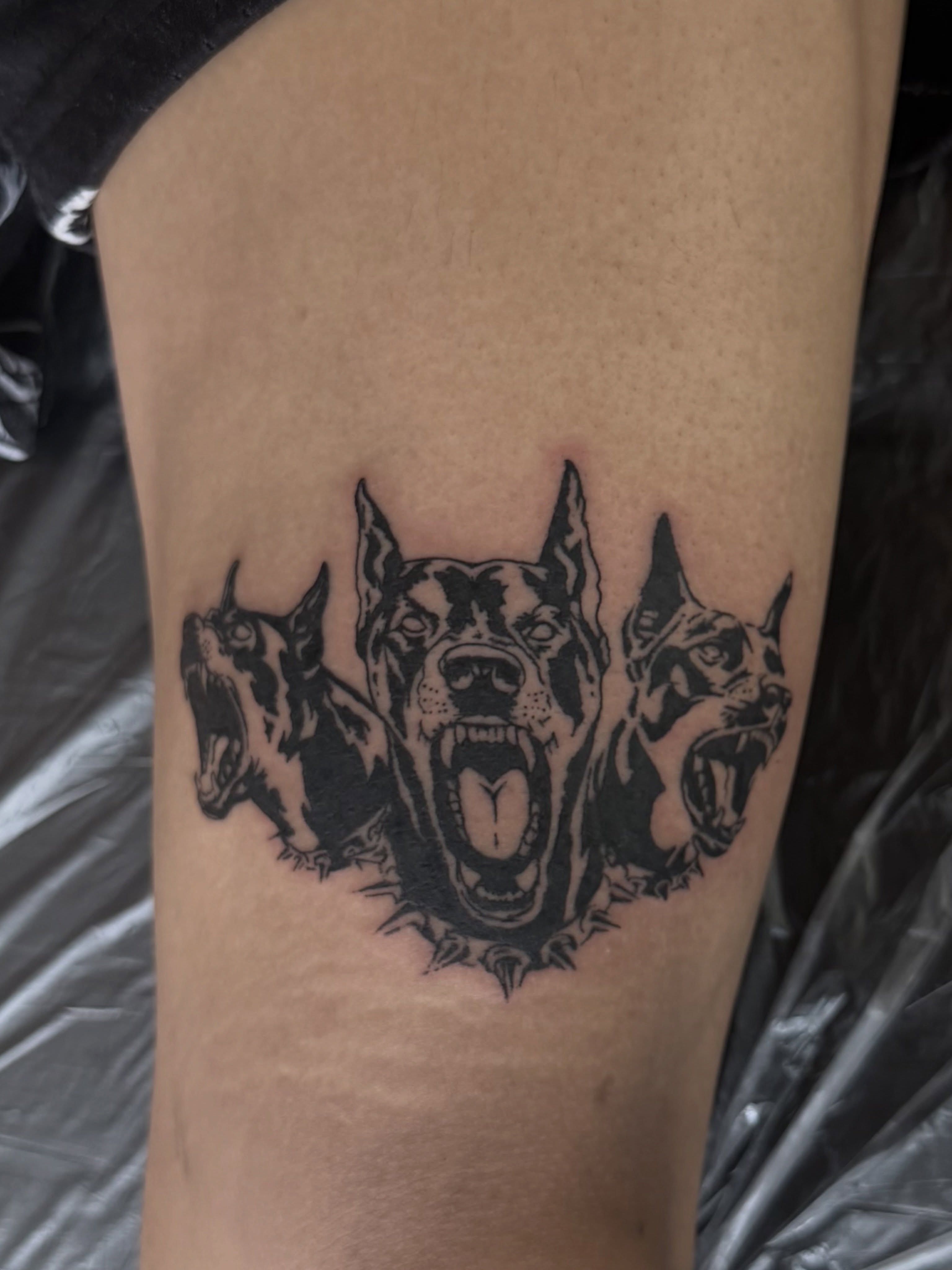 Three dogs black and grey tattoo on the thigh by Casper Tattoos Toronto
