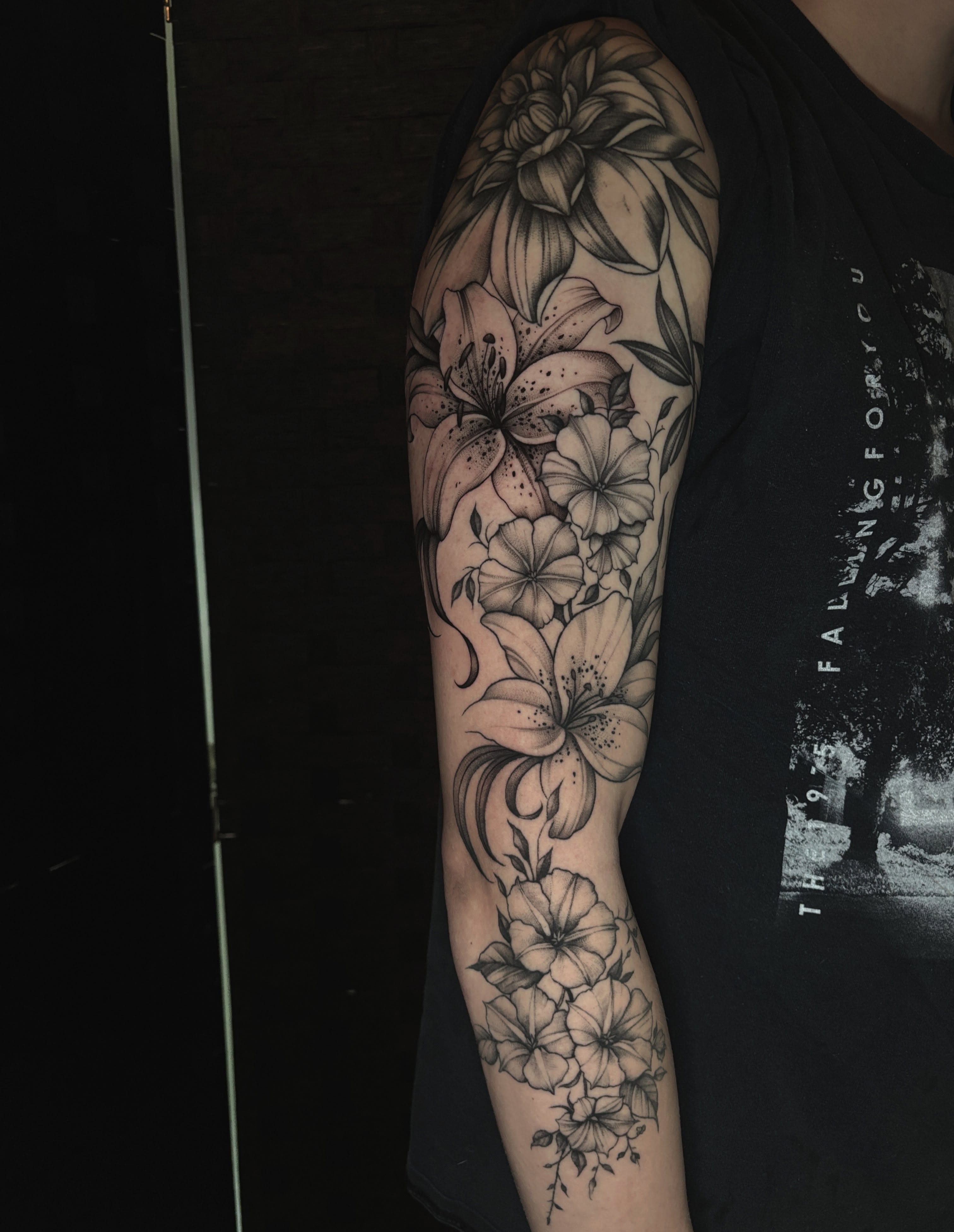Lilies and flowers black and grey tattoo on the forearm by Emma Cotter