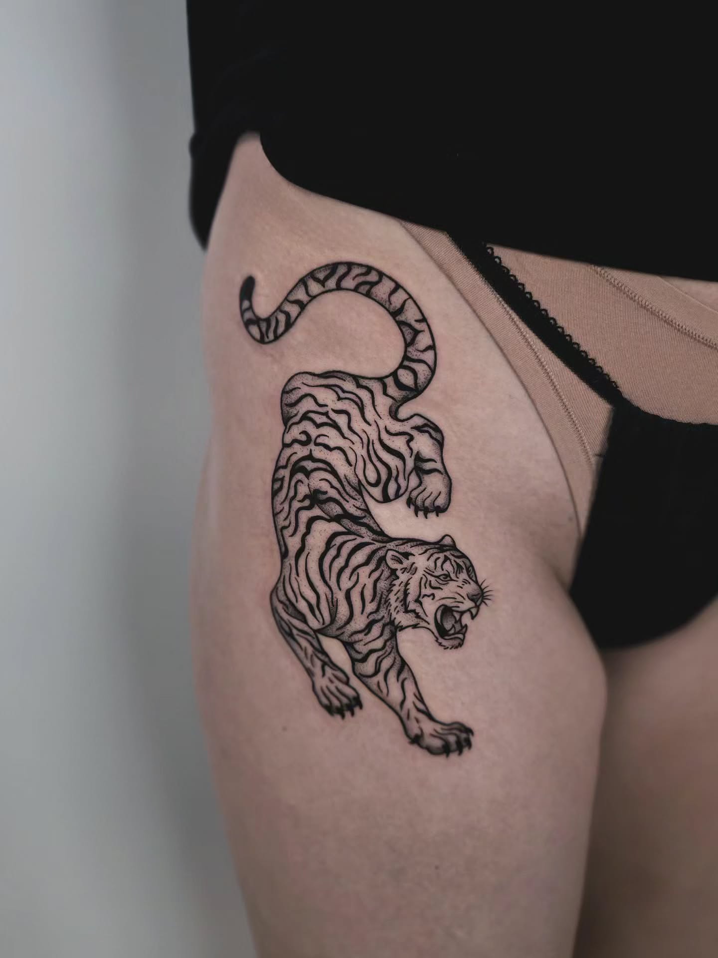 Tiger black and grey tattoo on the thigh by Kirstie Lew Tattoo