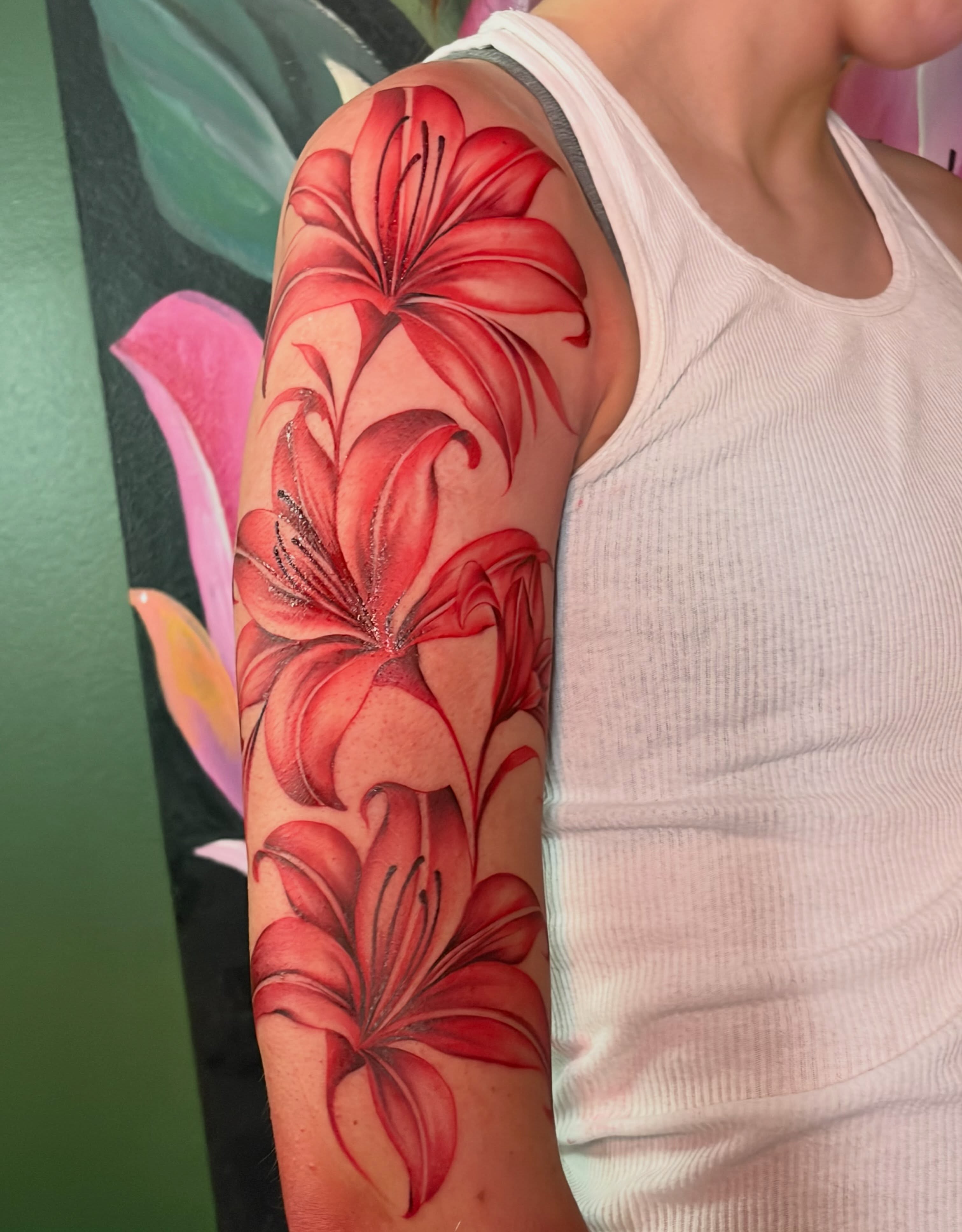 Red lilies realism tattoo on the forearm by Tattedbytrinn