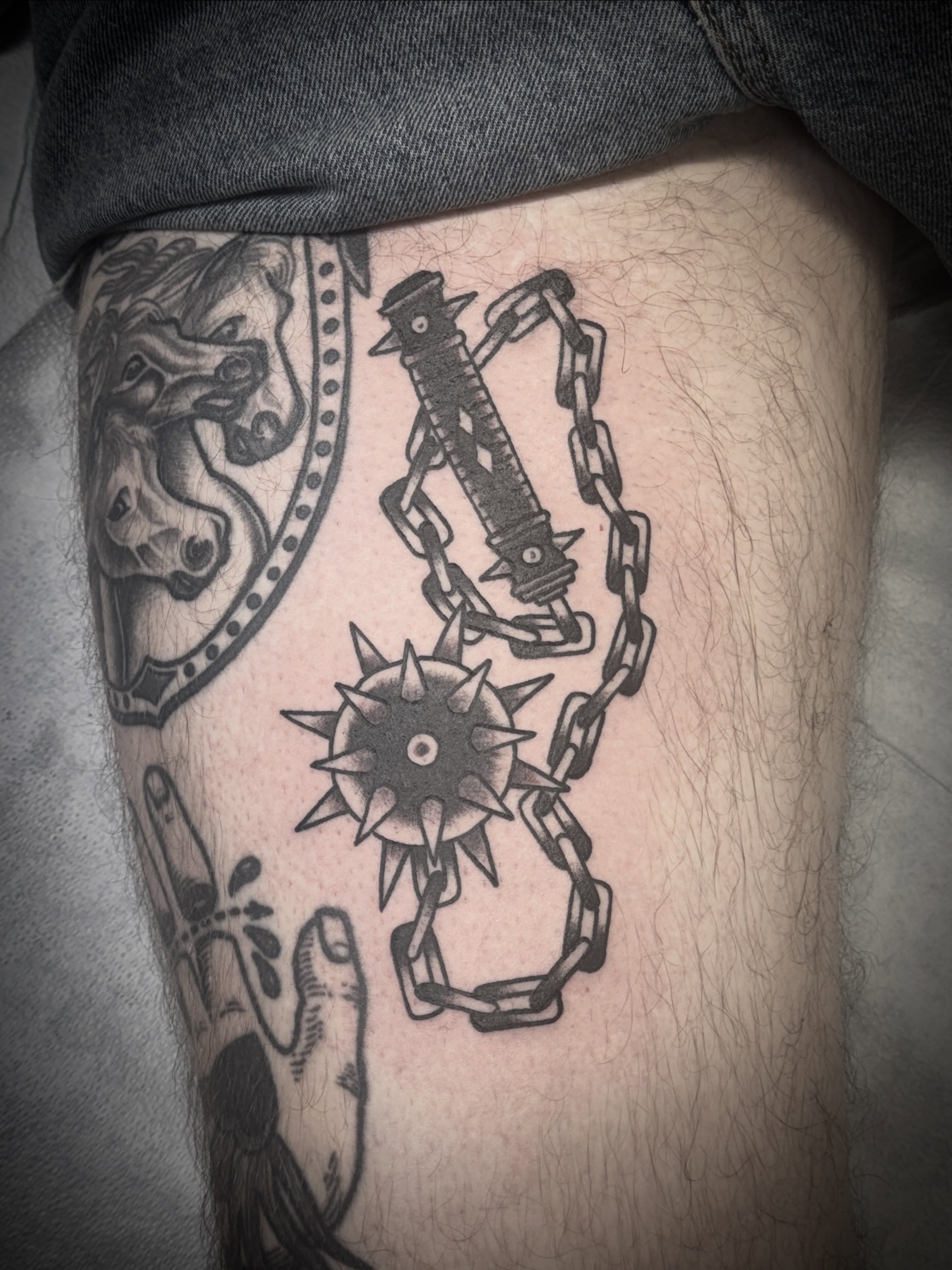 Chains and spikes black and grey tattoo on the thigh by Aaron ulfstam