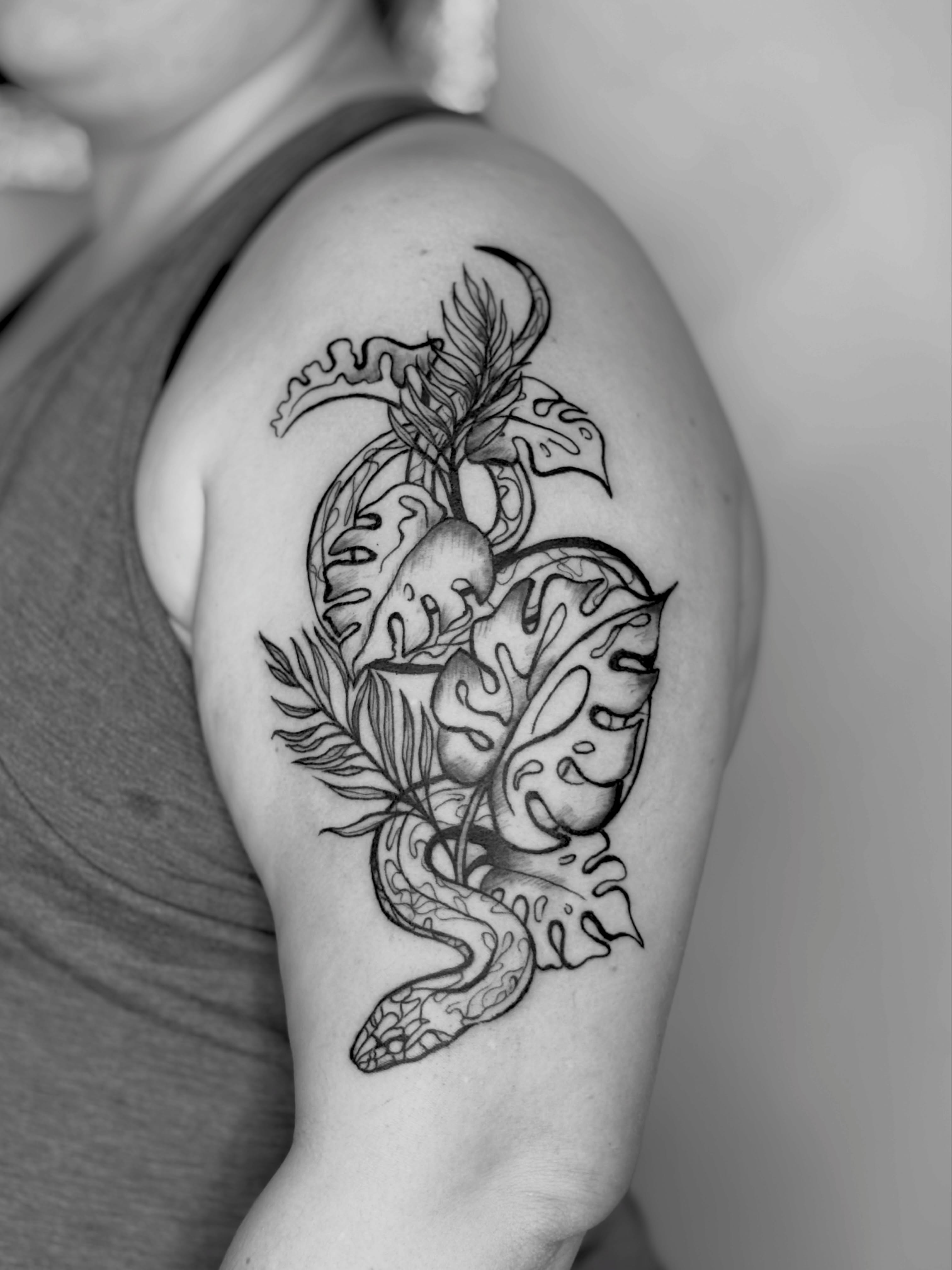 Snake and leaves black and grey tattoo on the shoulder by Sarah