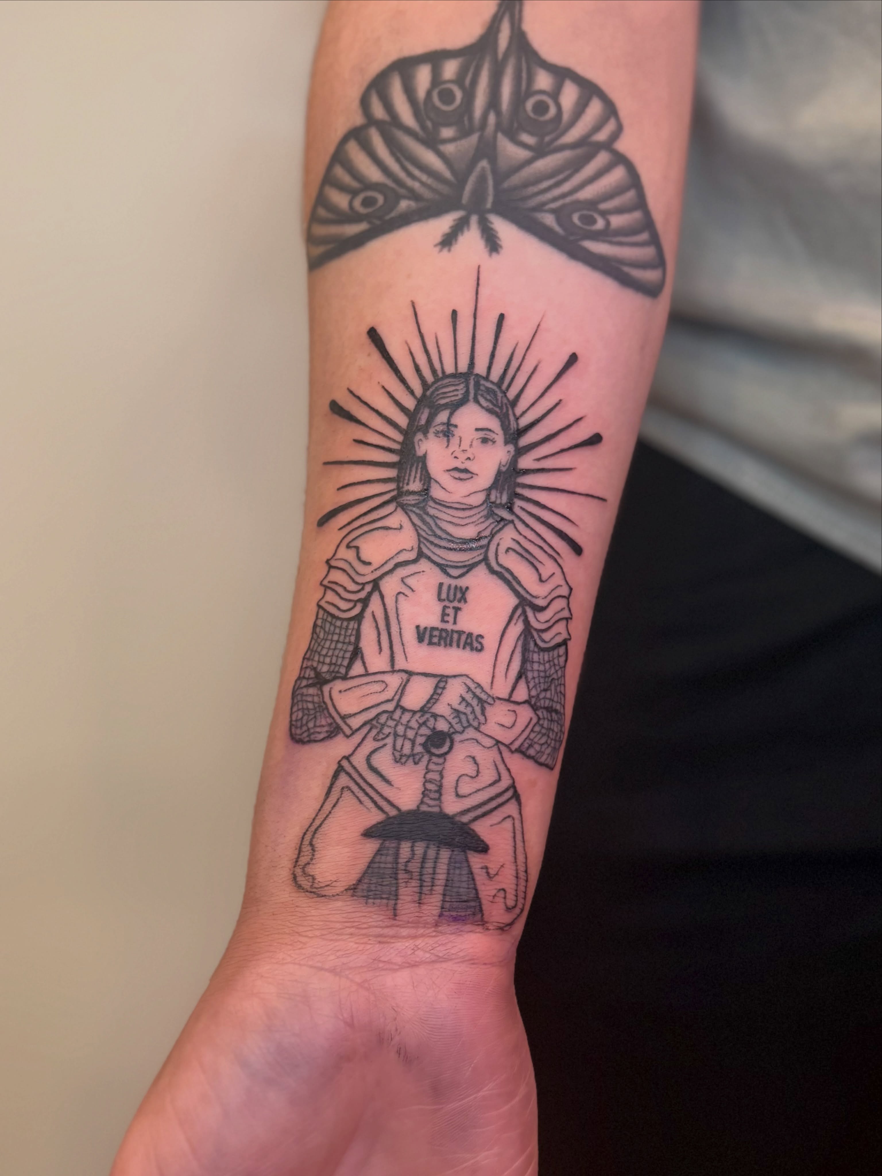 Woman with moth black and grey tattoo on the forearm by Sarah