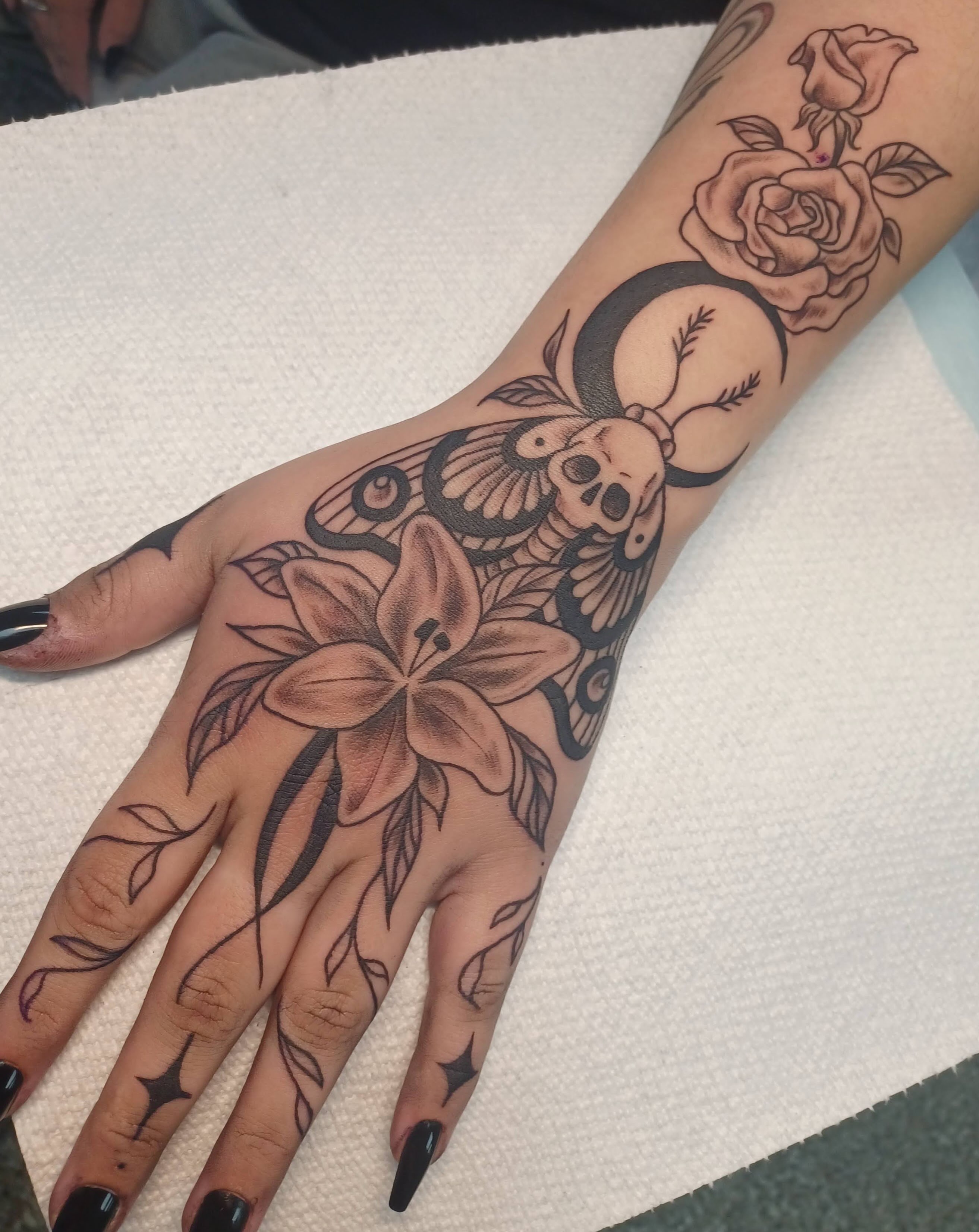 Lily and skull ornamental tattoo on the hand by Abi