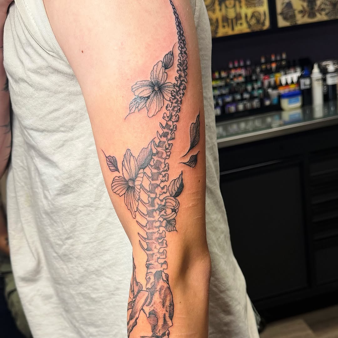 Spine with flowers black and grey tattoo on the forearm by Emily