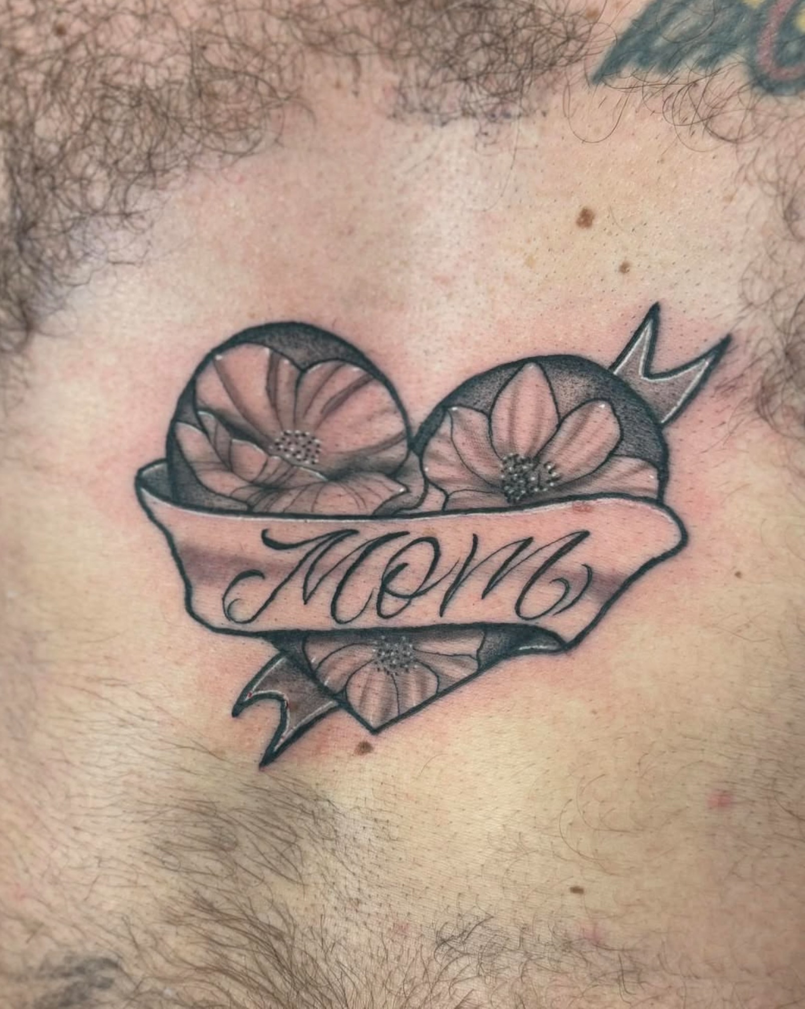 Flower and ribbon American traditional tattoo on the chest by Israel Jacob Woehler