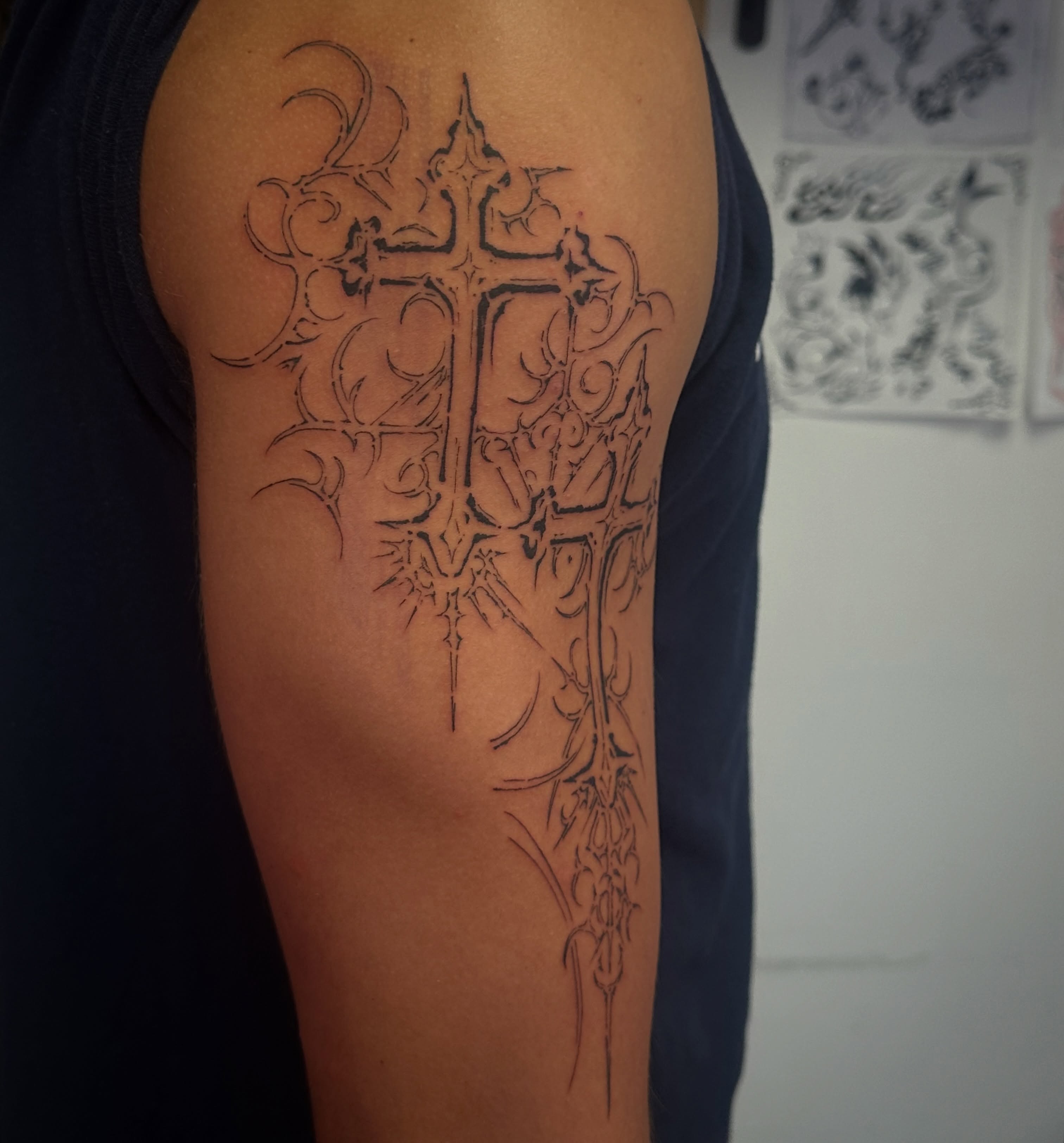 Cross with ornate details black and grey tattoo on the upper arm by TATTOOLIZARD (James)