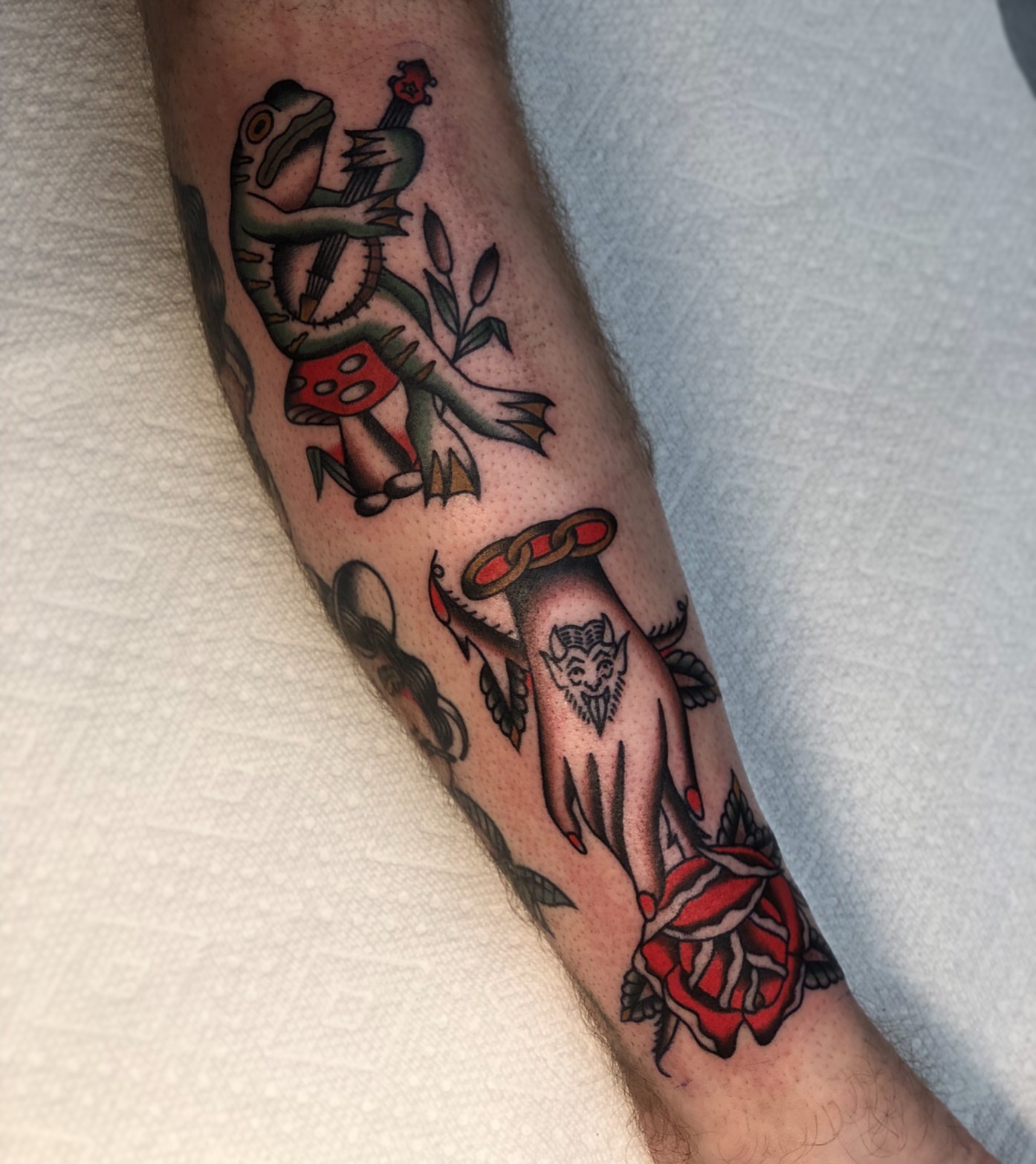 Frog playing guitar American traditional tattoo on the forearm by EVA Traditional Tattoos