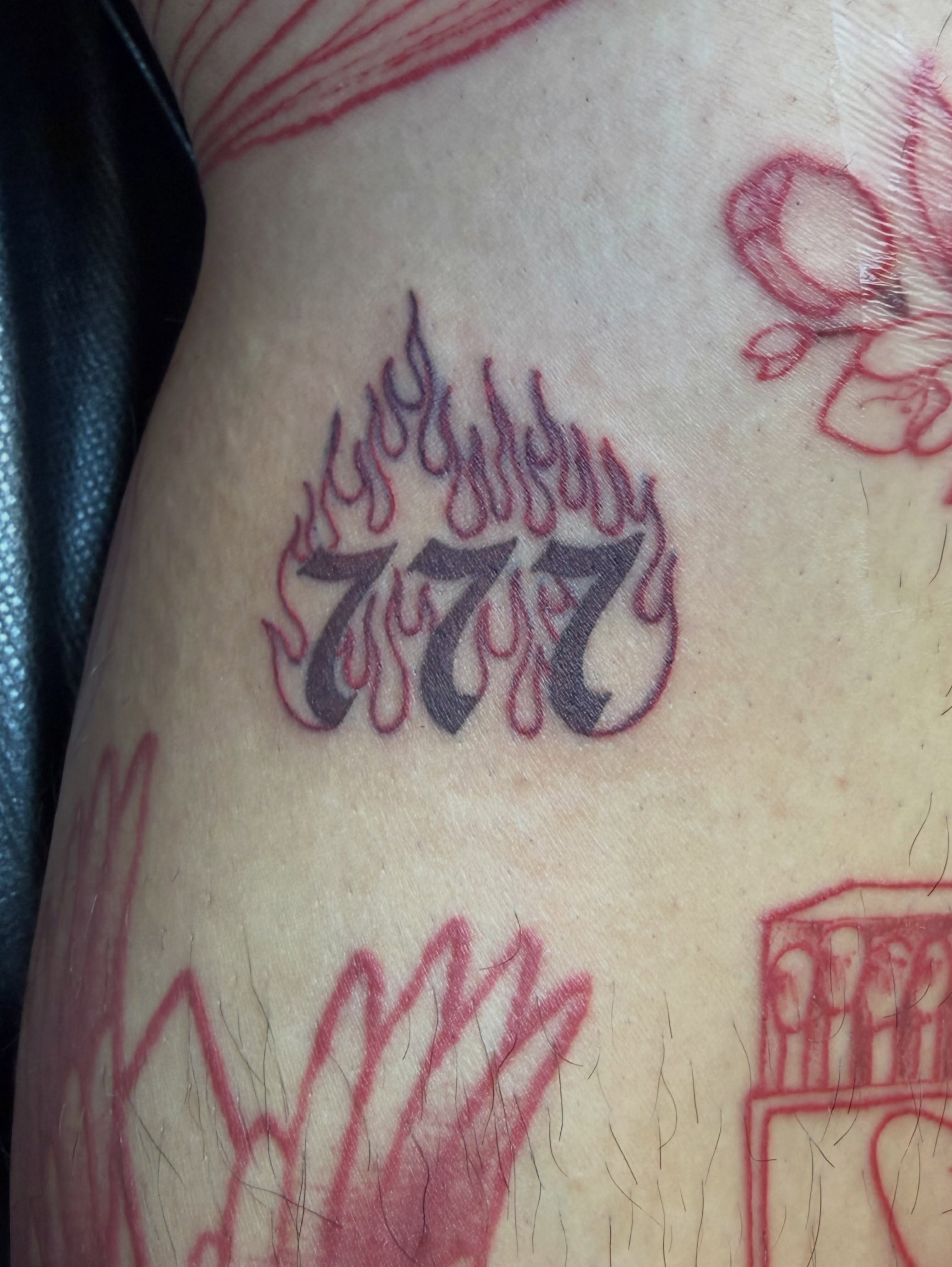 Flaming number 777 lettering script tattoo on the thigh by Taytum Marsing, Salt Lake City, Utah
