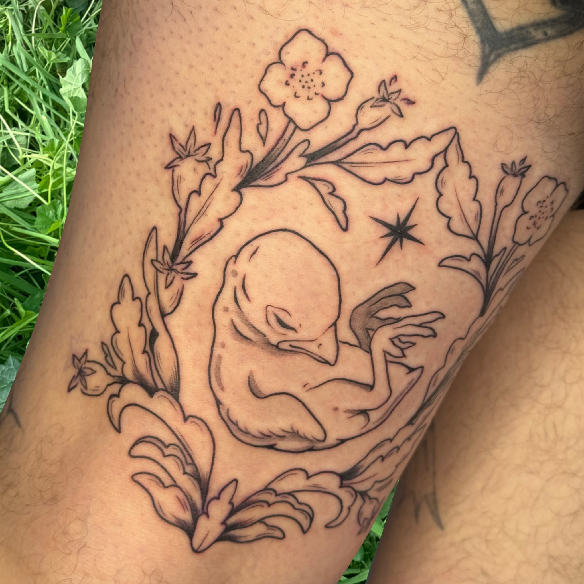 Bird and floral wreath realism tattoo on the thigh by Ivy