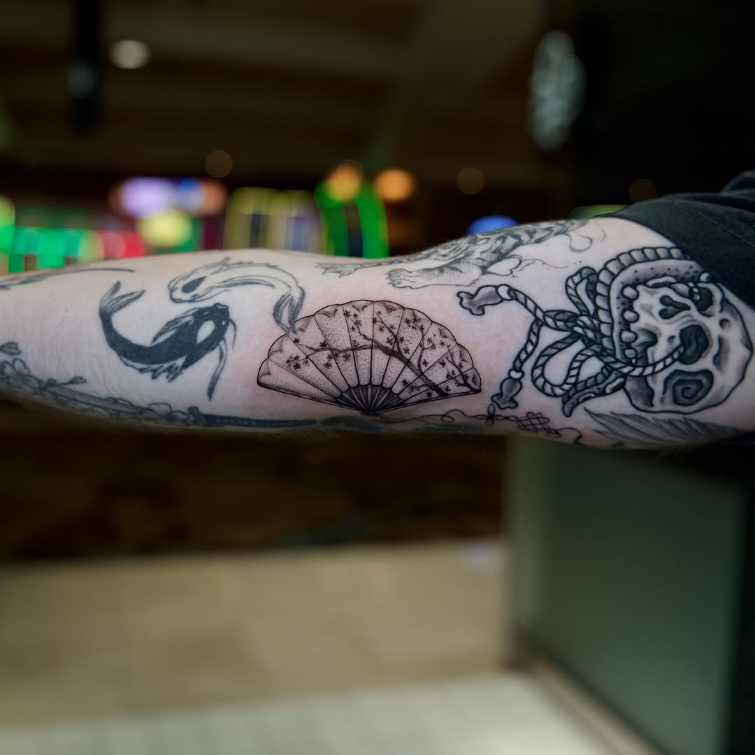 Fish, fan, skull, rope black and grey tattoo on the forearm by Raven Wood