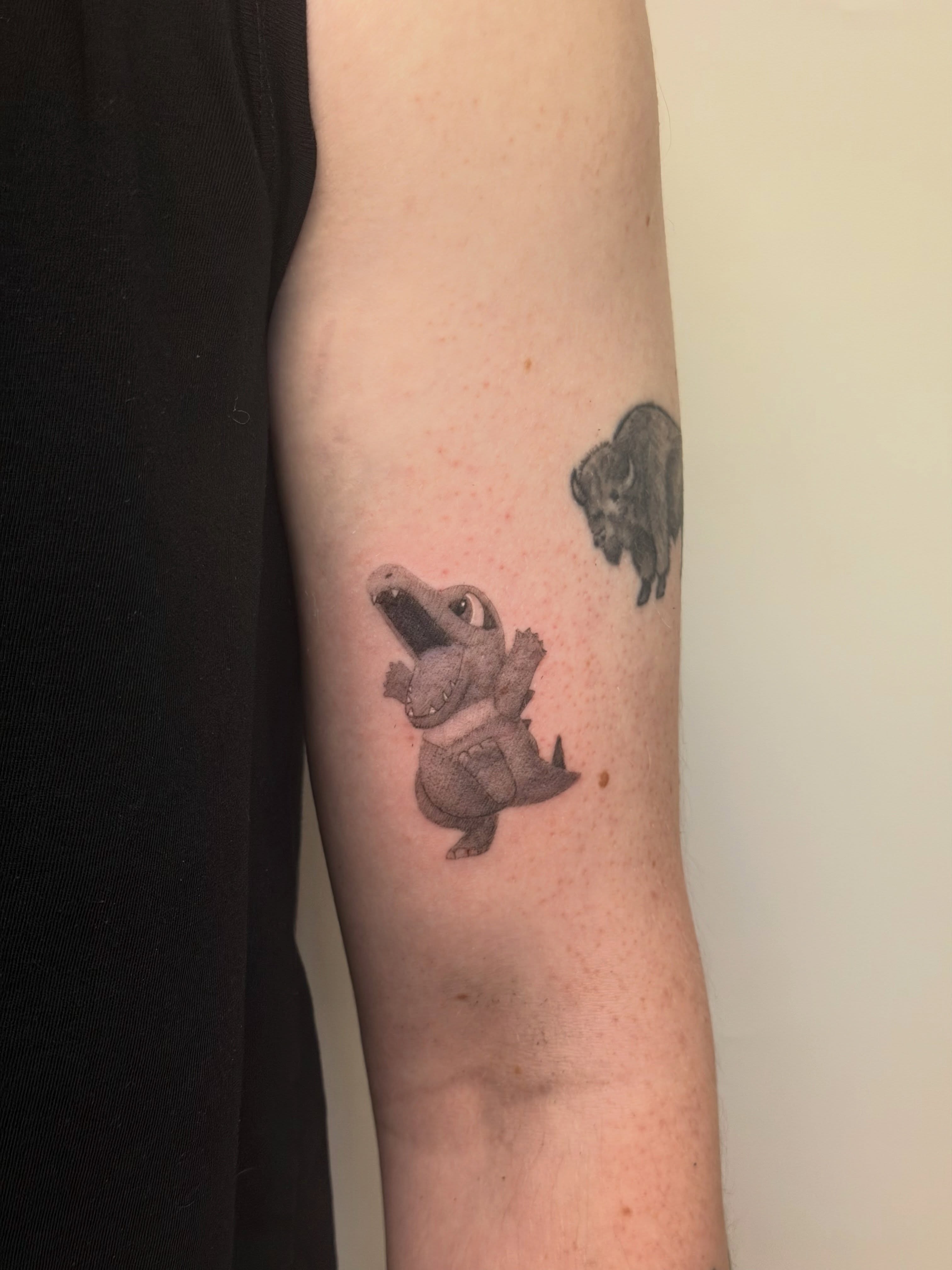 Dinosaur black and grey tattoo on the forearm by Alaska