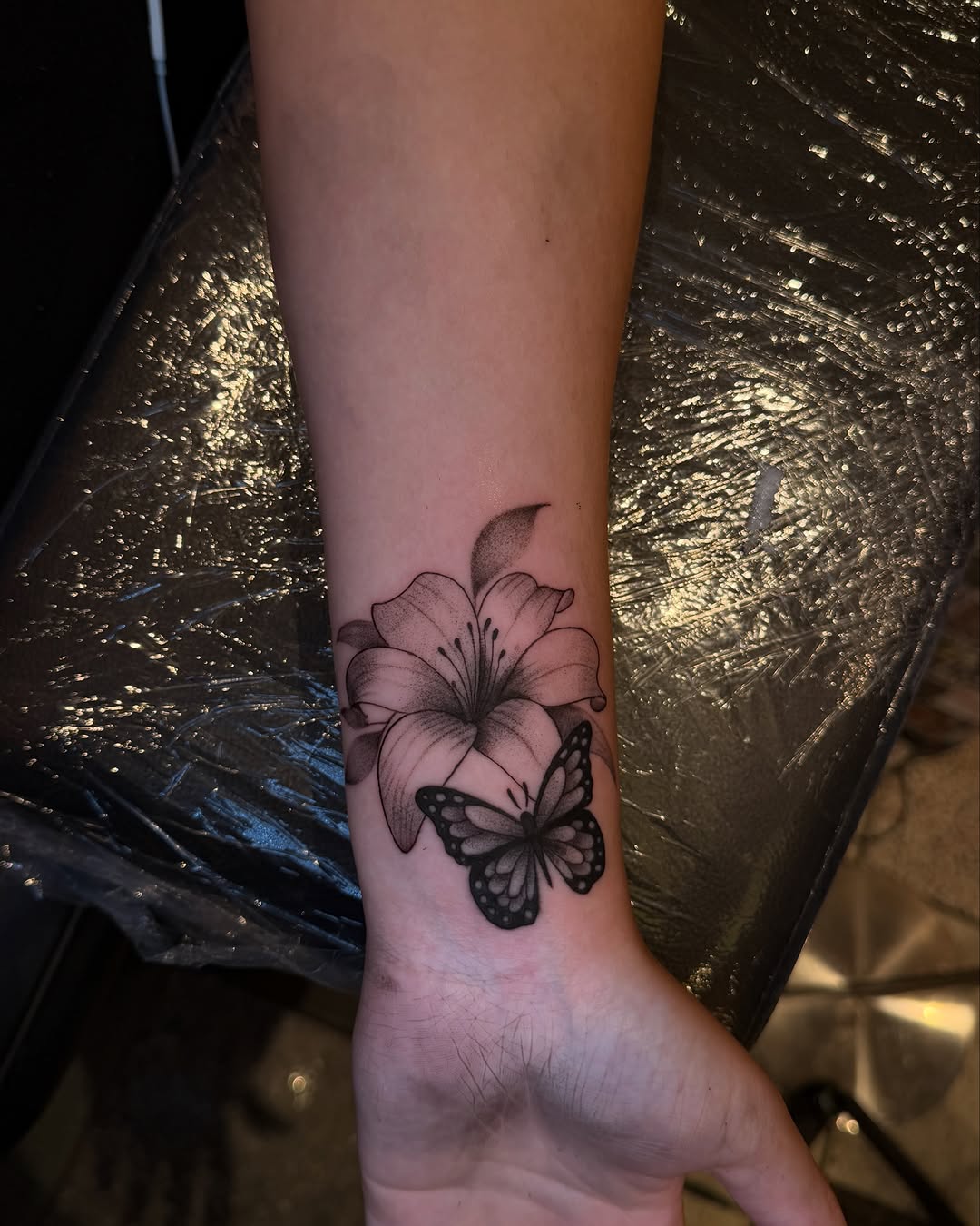 Lily and butterfly fine line tattoo on the forearm by ๐๐ข๐ฃ๐ฑ ๐๐ฆ๐ฑ๐ฌ ๐๏ธ