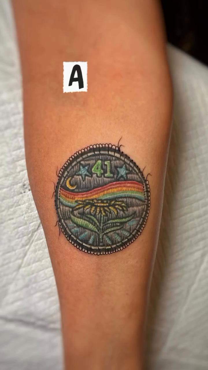 Circular emblem with rainbow and stars tattoo on the forearm by Yana Aizen
