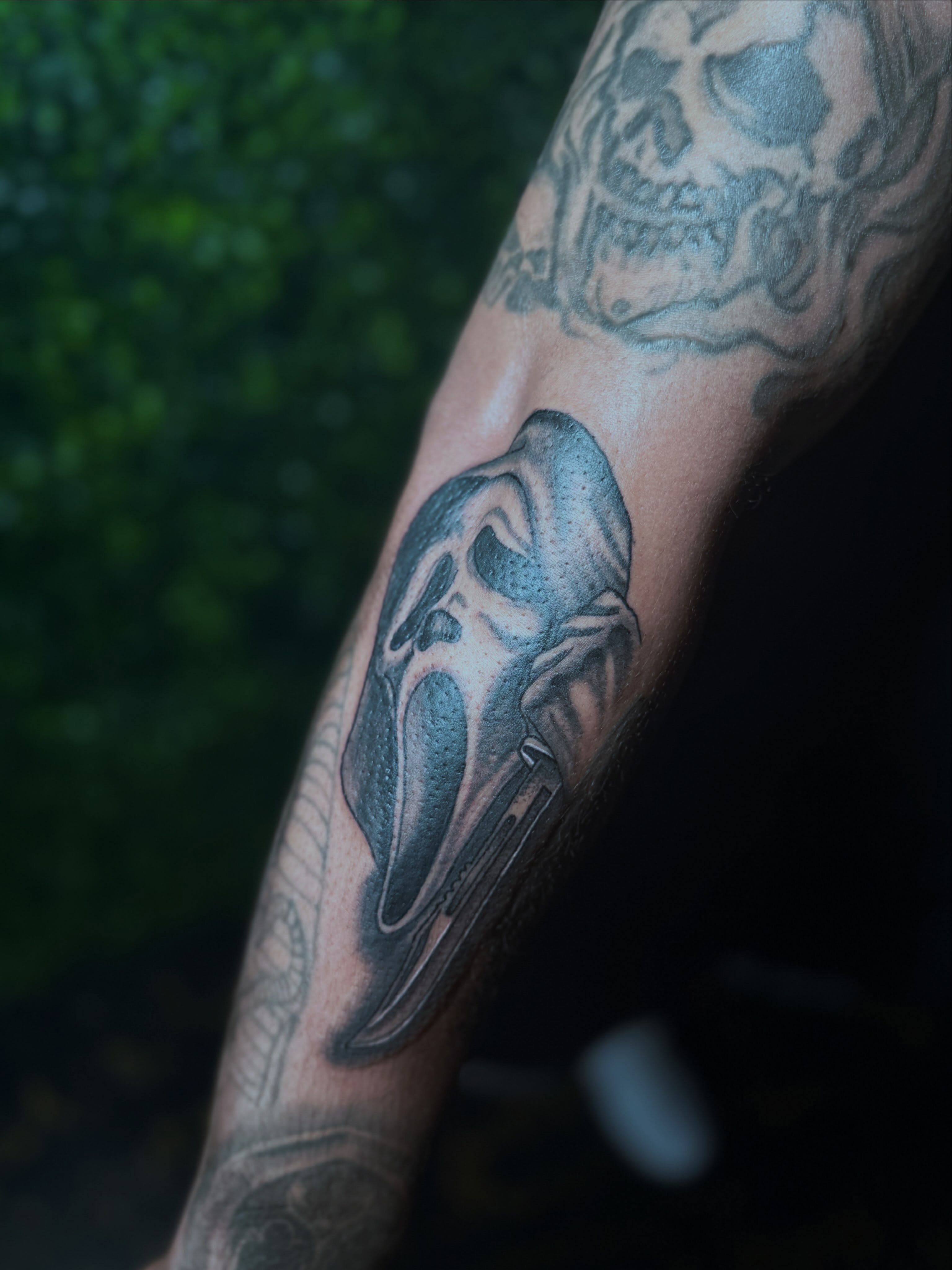 Mask black and grey tattoo on the forearm by Alesia