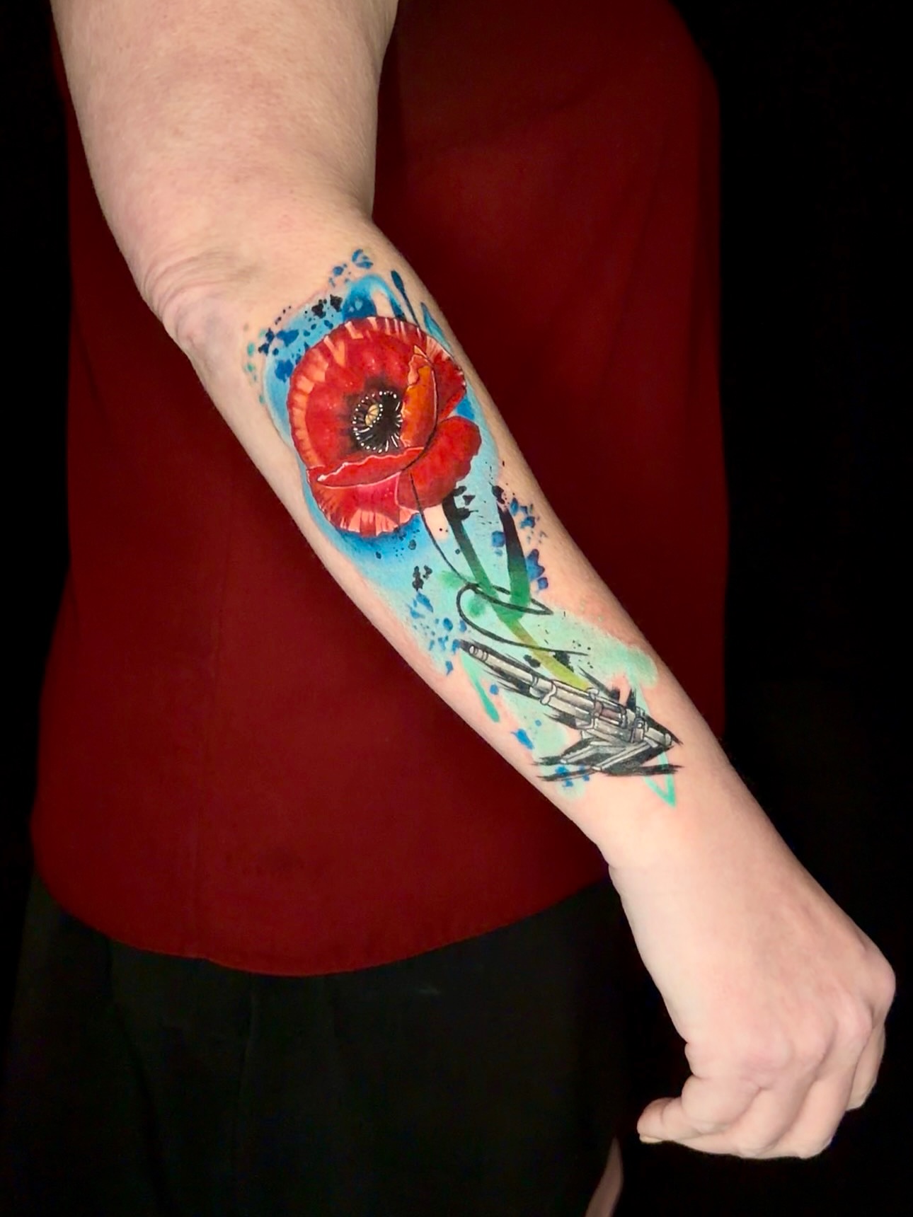 Poppy and gun watercolor tattoo on the forearm by Goga