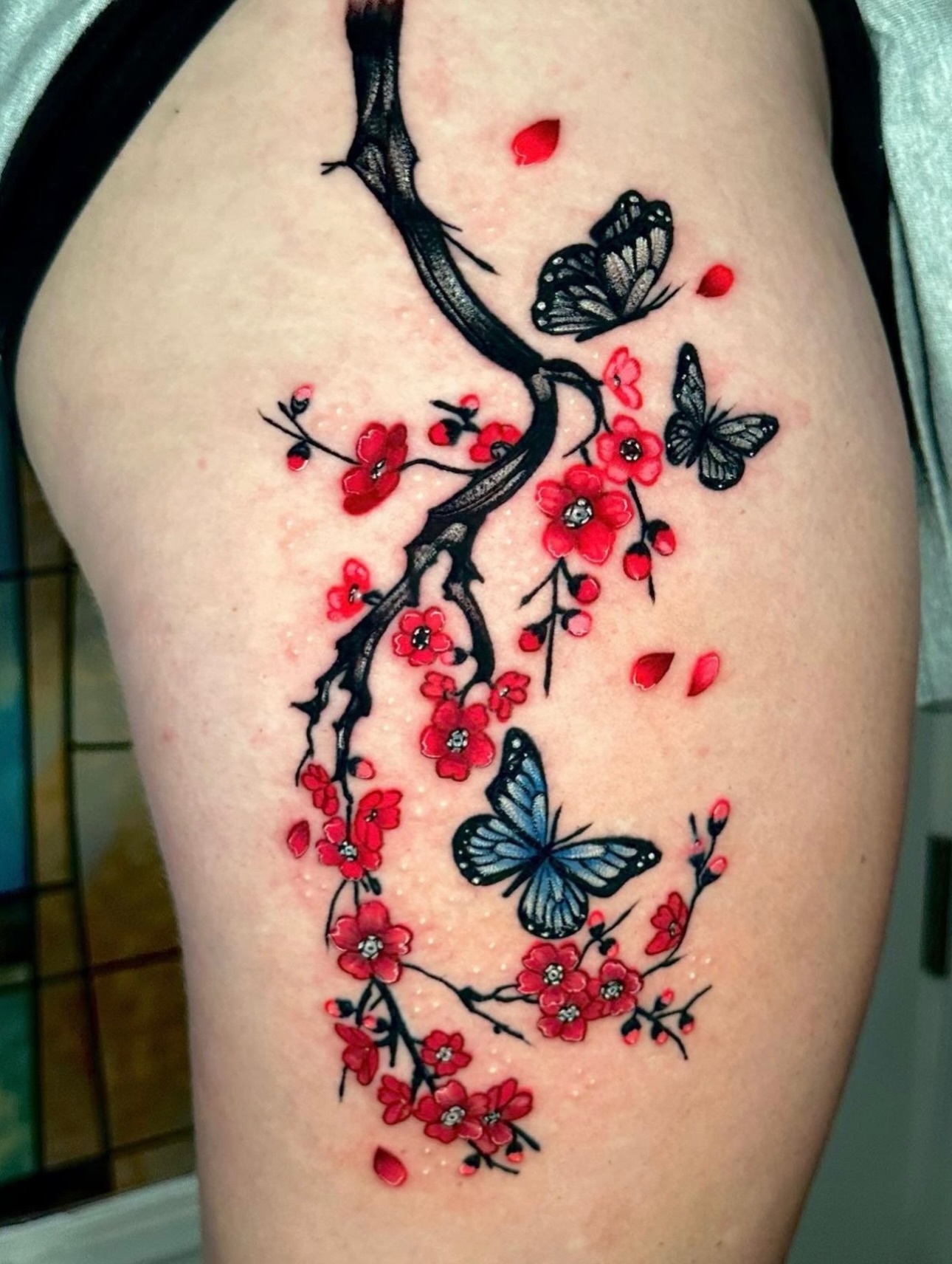 Cherry blossoms and butterflies dotwork tattoo on the thigh by Goga