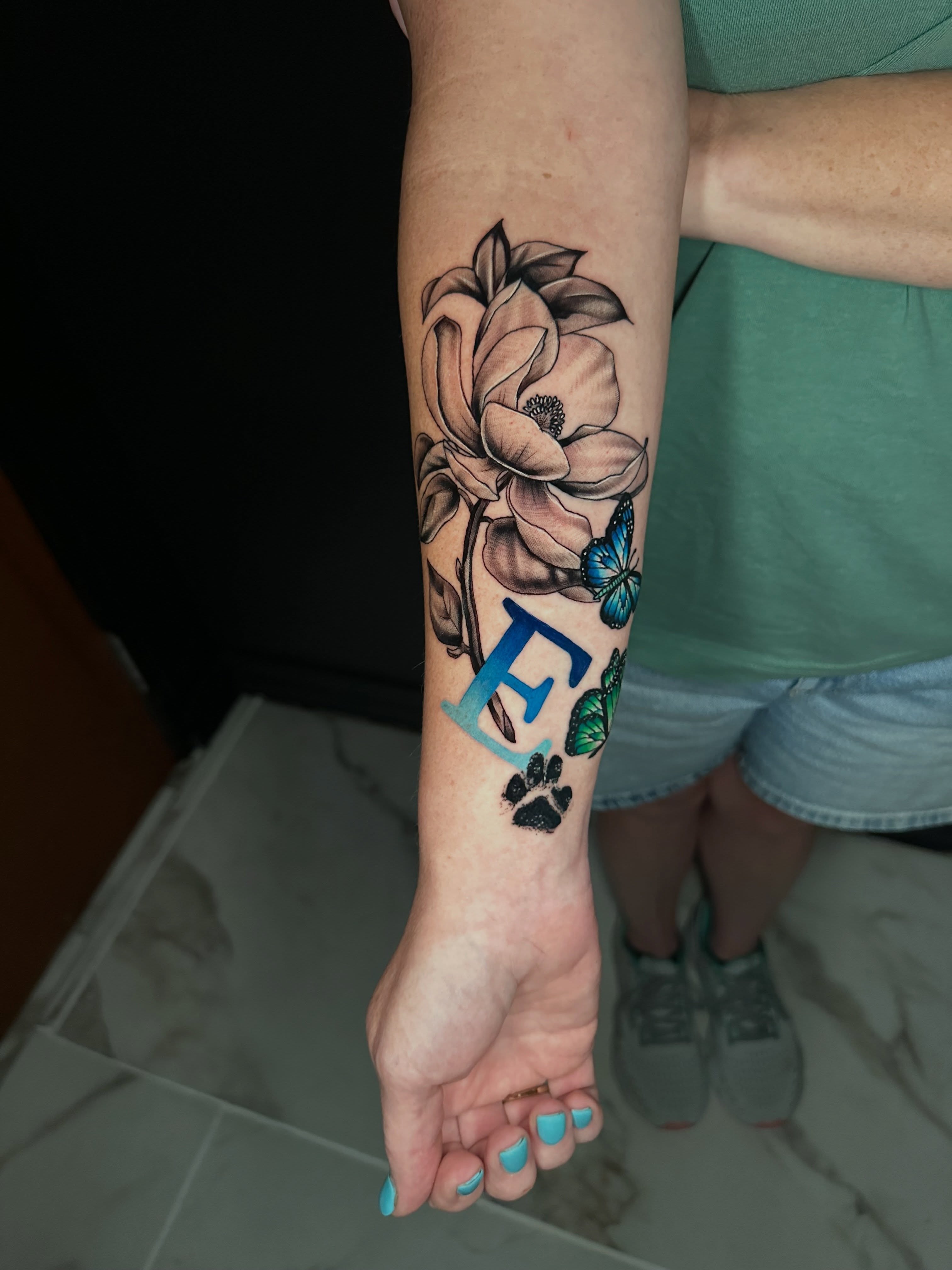 Flower and paw print realism tattoo on the forearm by Goga