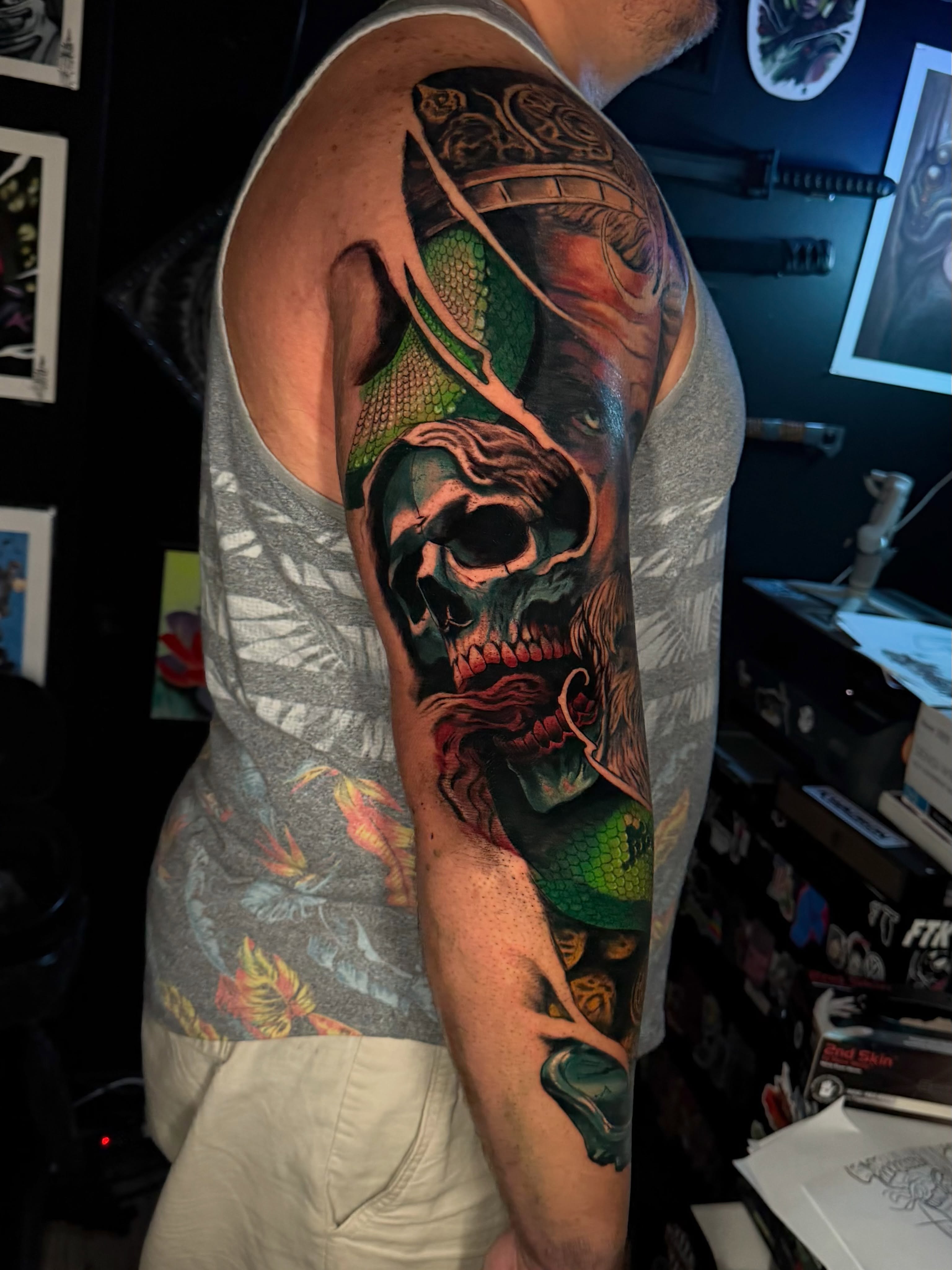 Skull and snake dark realism tattoo on the upper arm by Dean Rogers