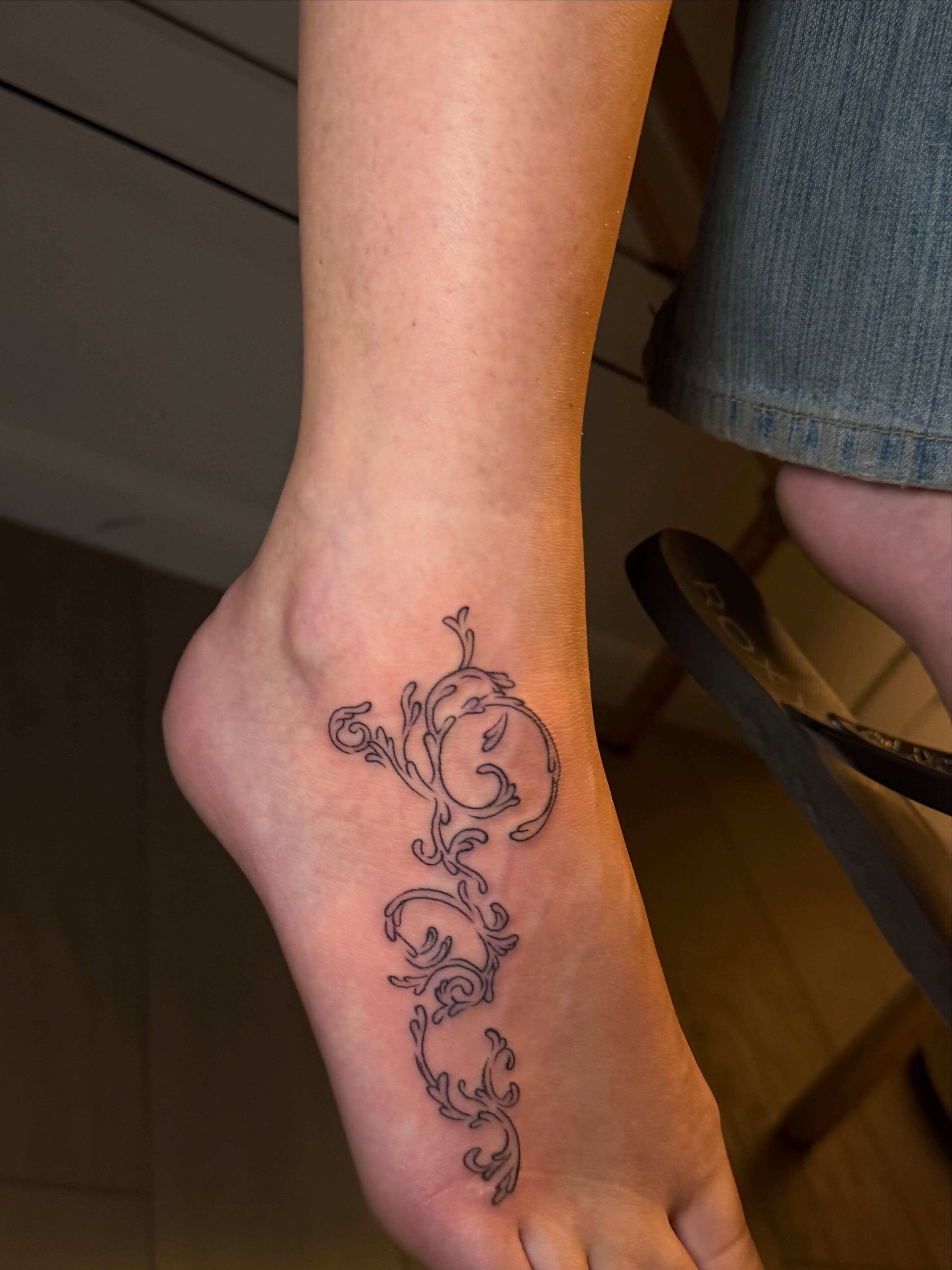 Scrollwork fine line tattoo on the foot by tattoo artist (mollz)