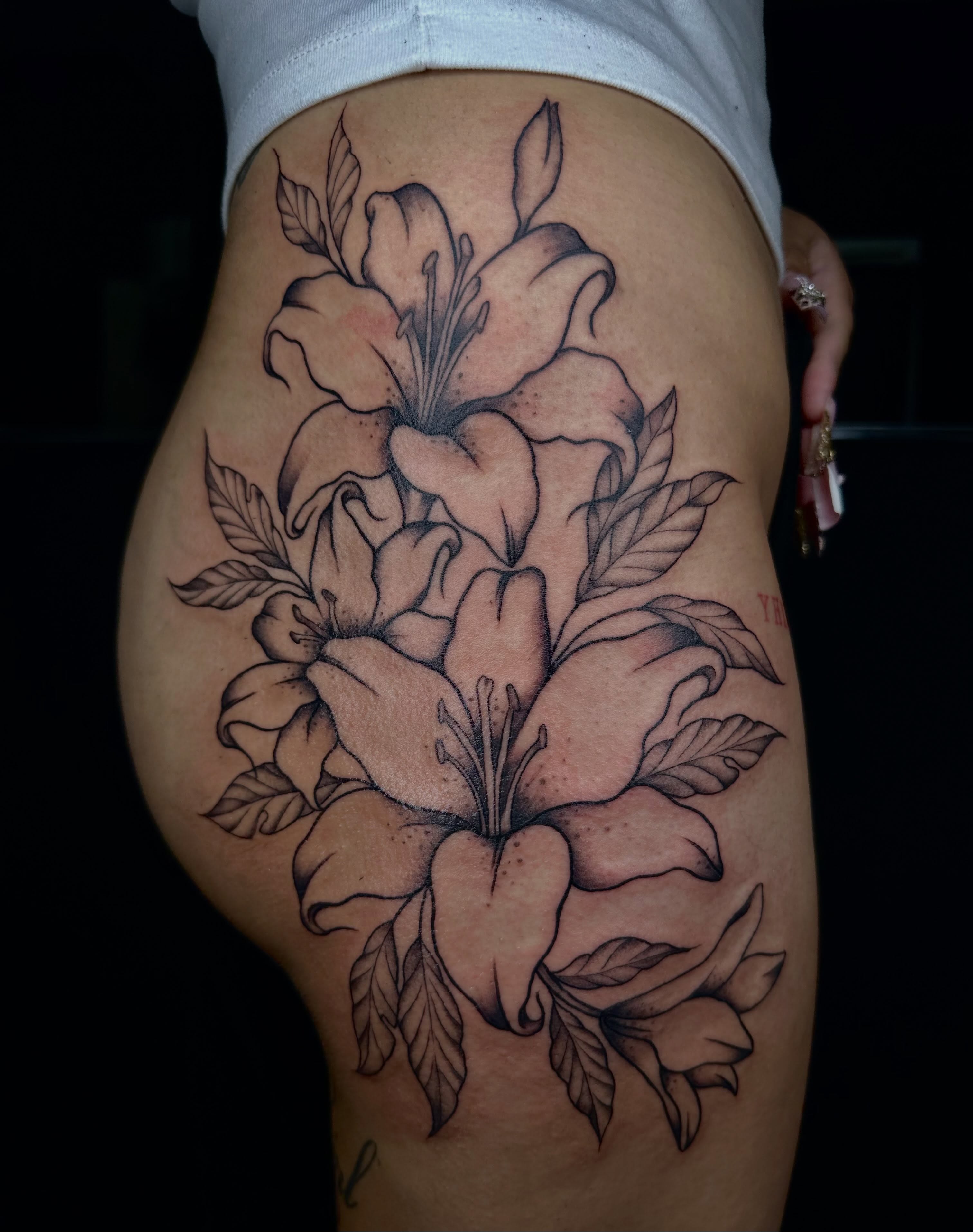 Lilies black and grey tattoo on the thigh by emma christine