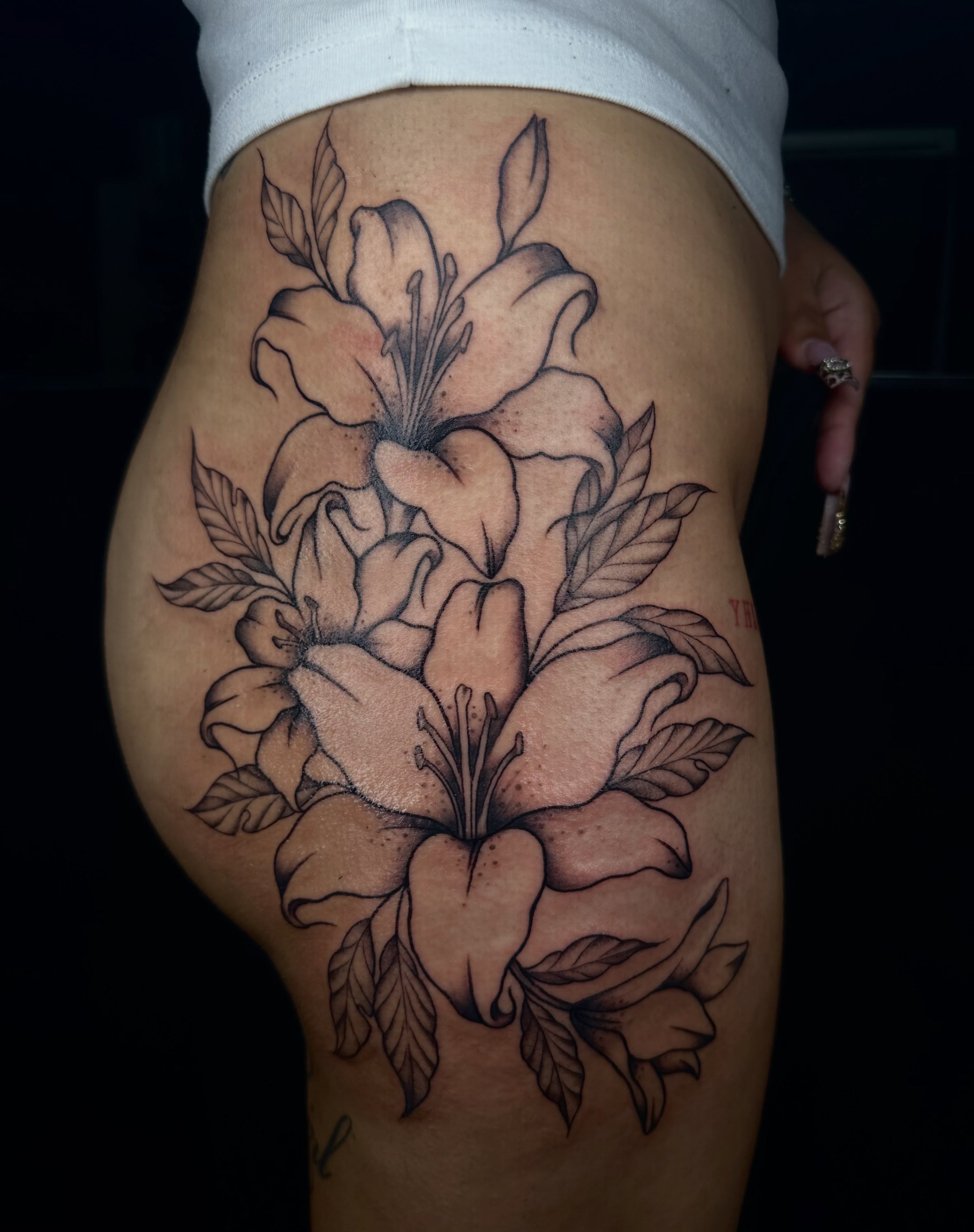 Lilies black and grey tattoo on the thigh by emma christine