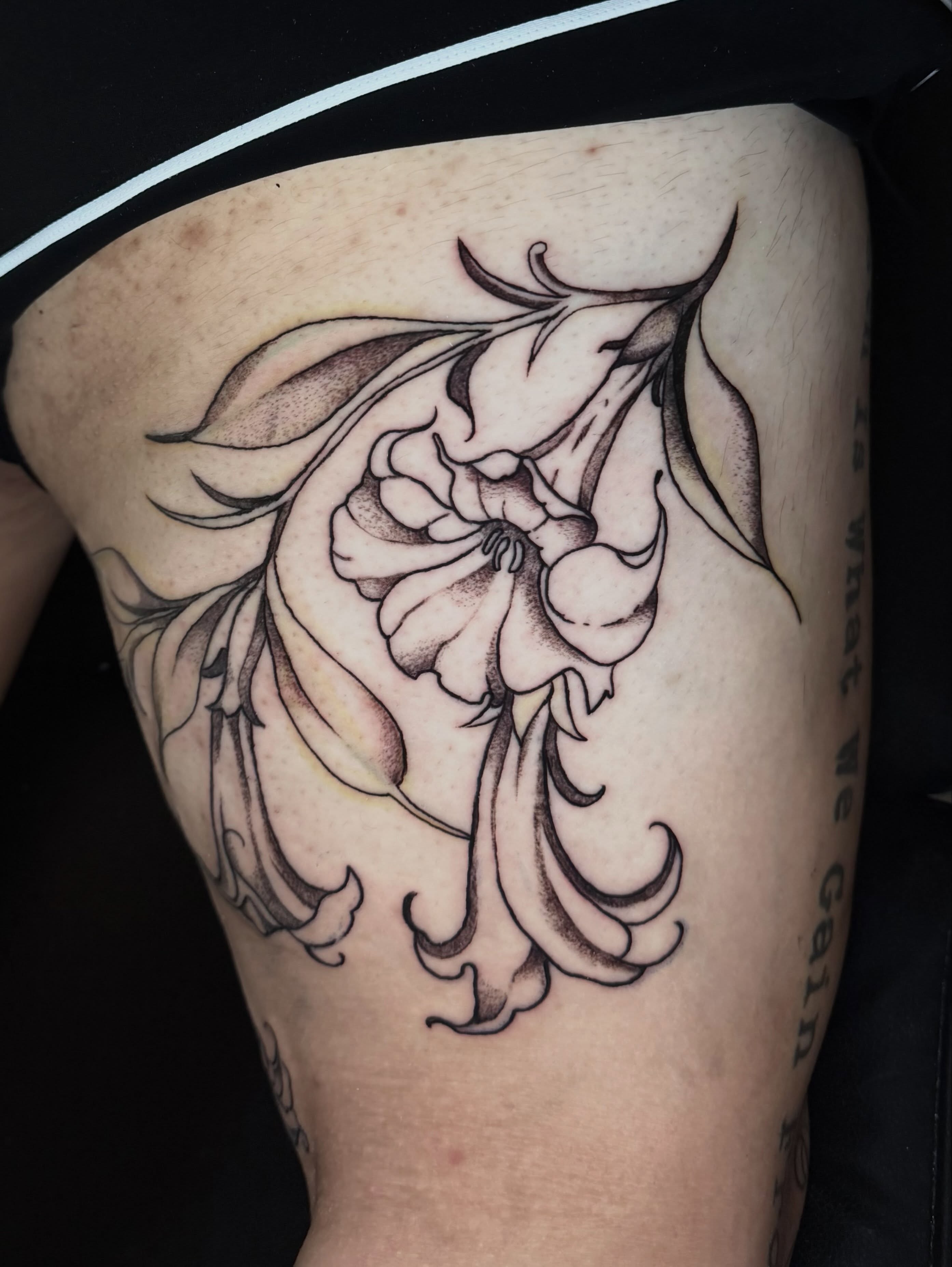 Floral design black and grey tattoo on the thigh by Gigi