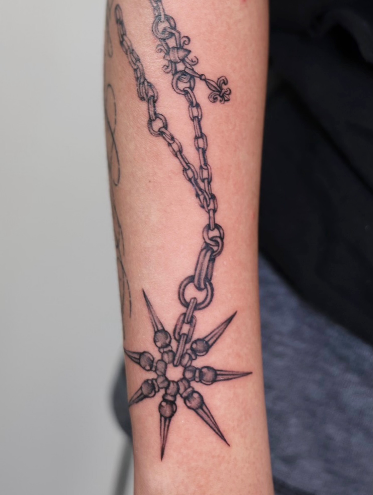 Chain and spiked ball black and grey tattoo on the forearm by @lovechasetattoo