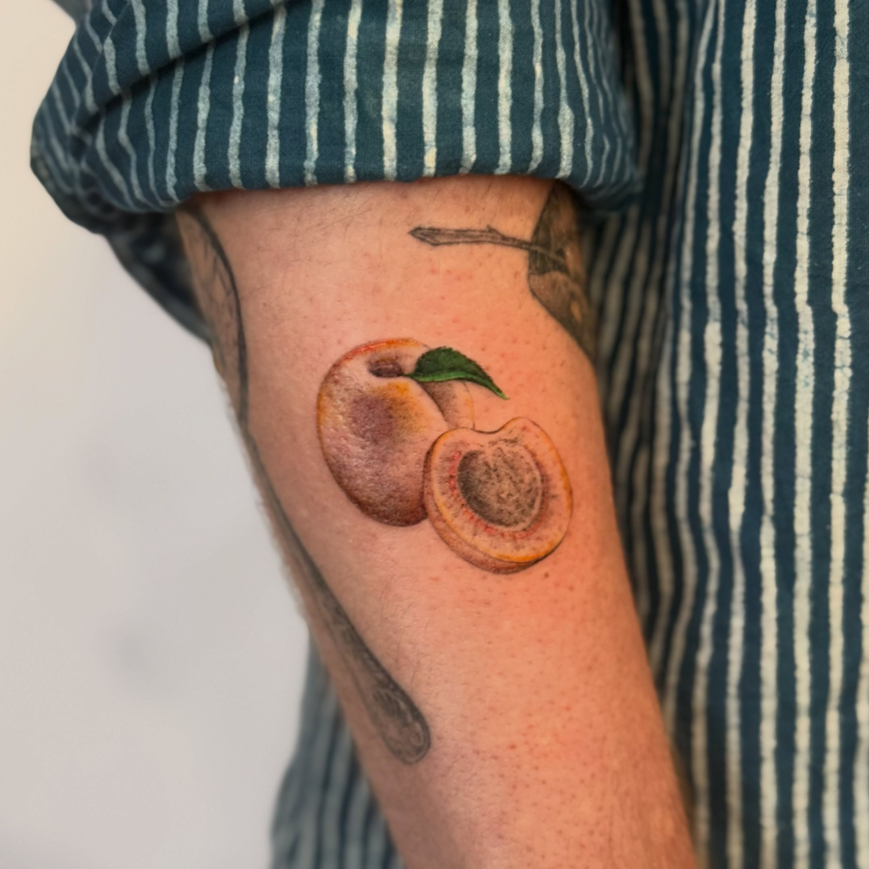 Peach realism tattoo on the forearm by bre