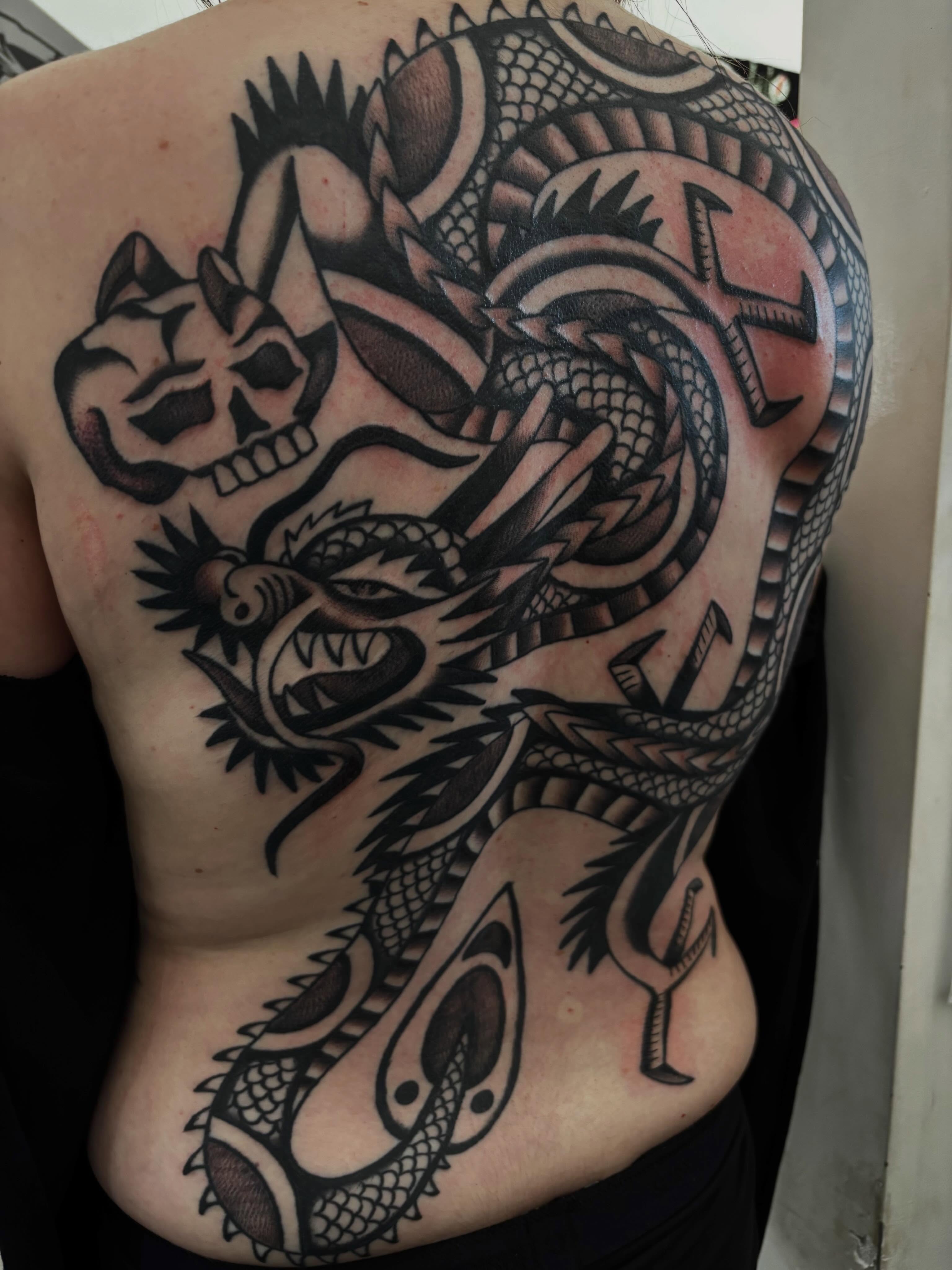 Dragon and skull American traditional tattoo on the back by Claire Anderson
