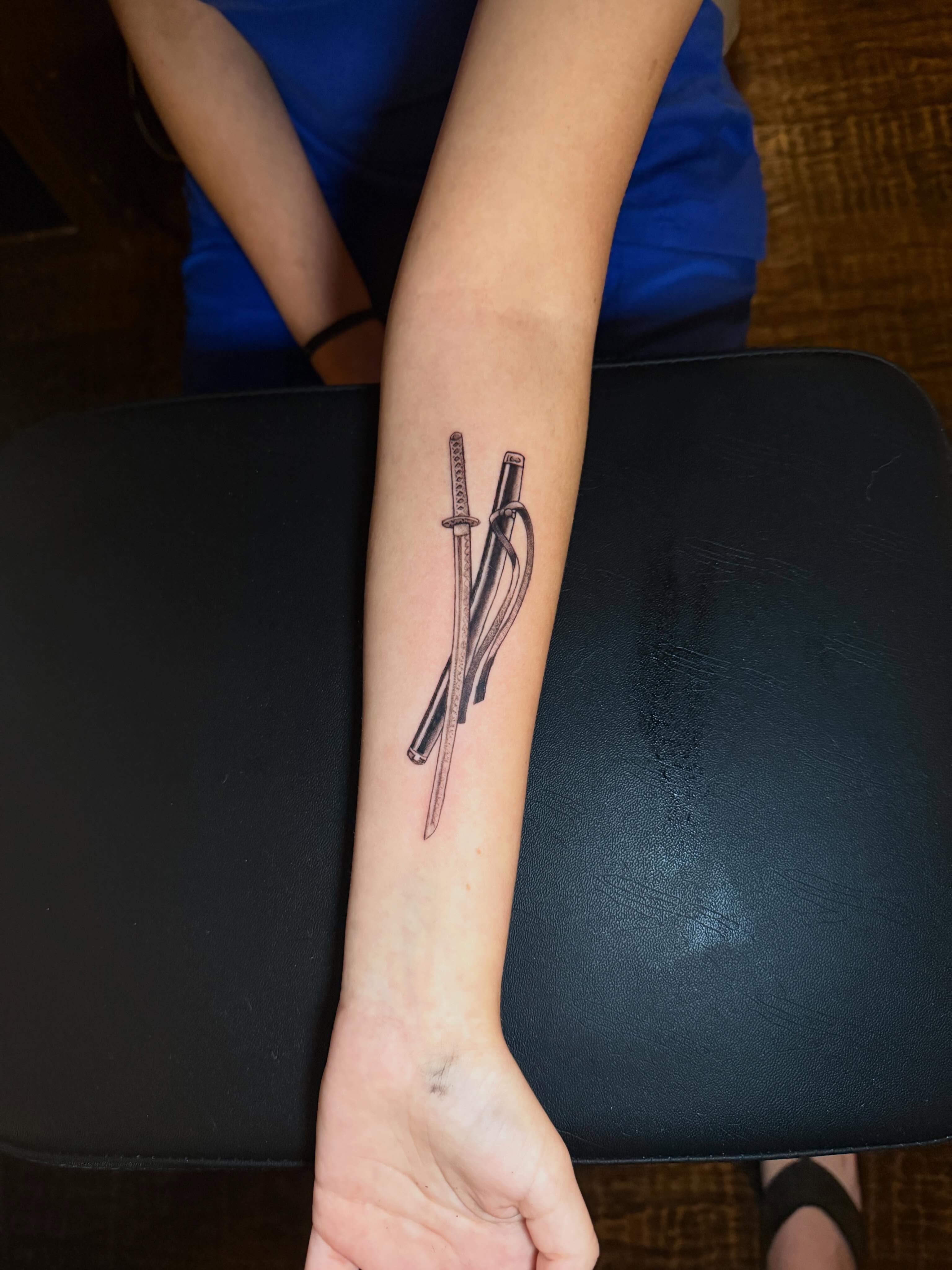 Katana and rope black and grey tattoo on the forearm by C.J.K. Roy