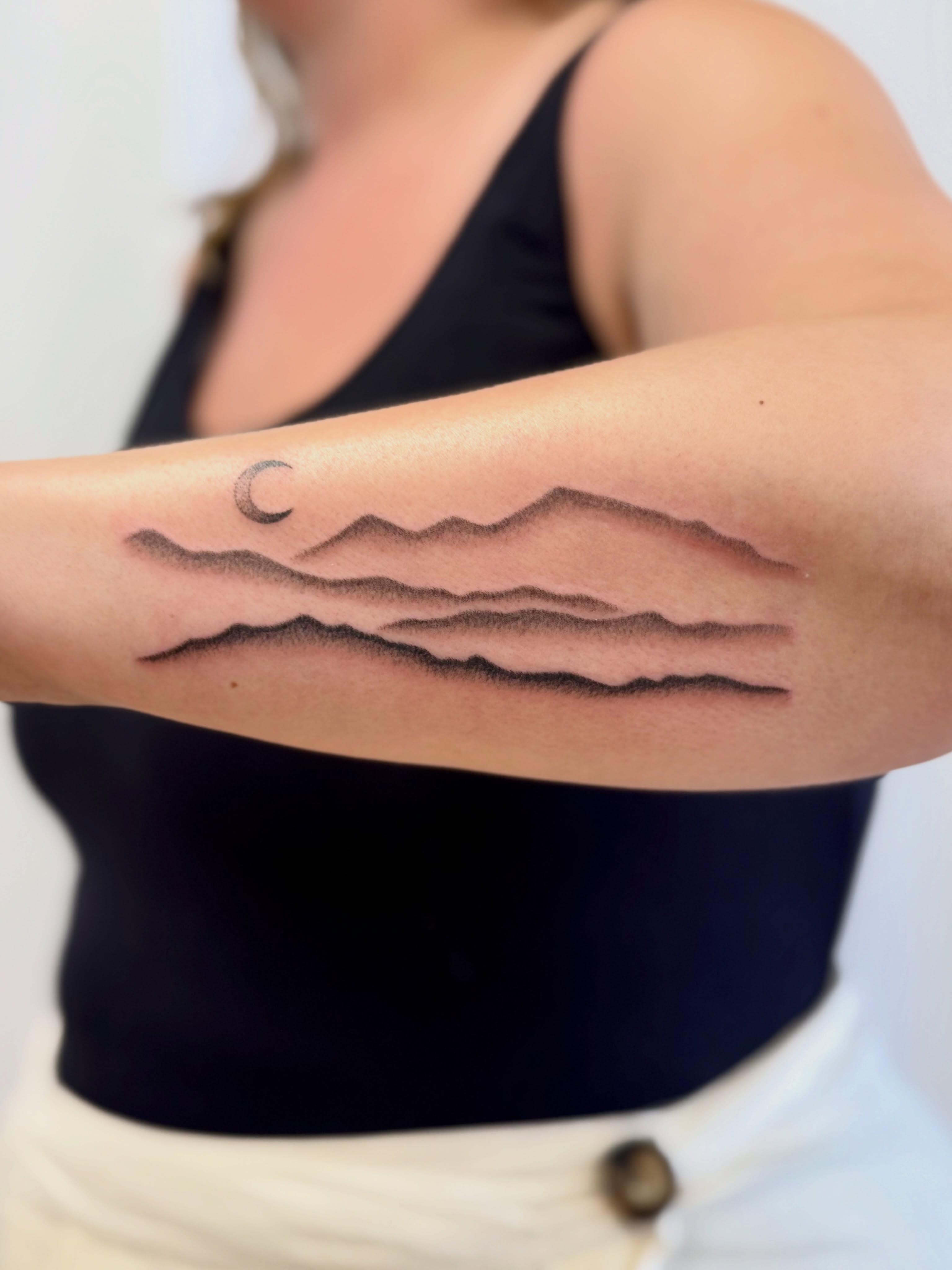 Waves and crescent moon dotwork tattoo on the forearm by Melia Mariko