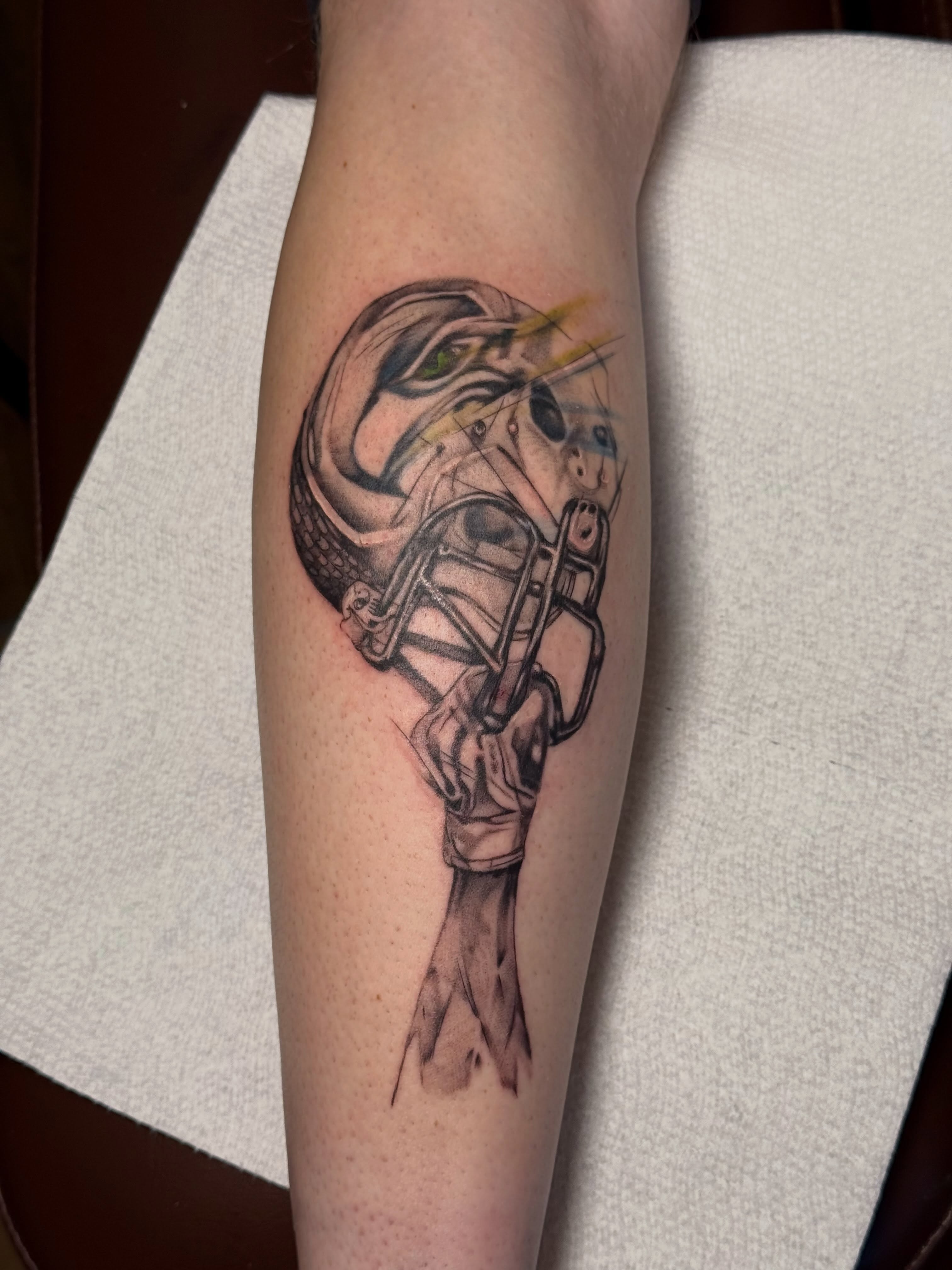Football helmet black and grey tattoo on the forearm by Lauren Horness