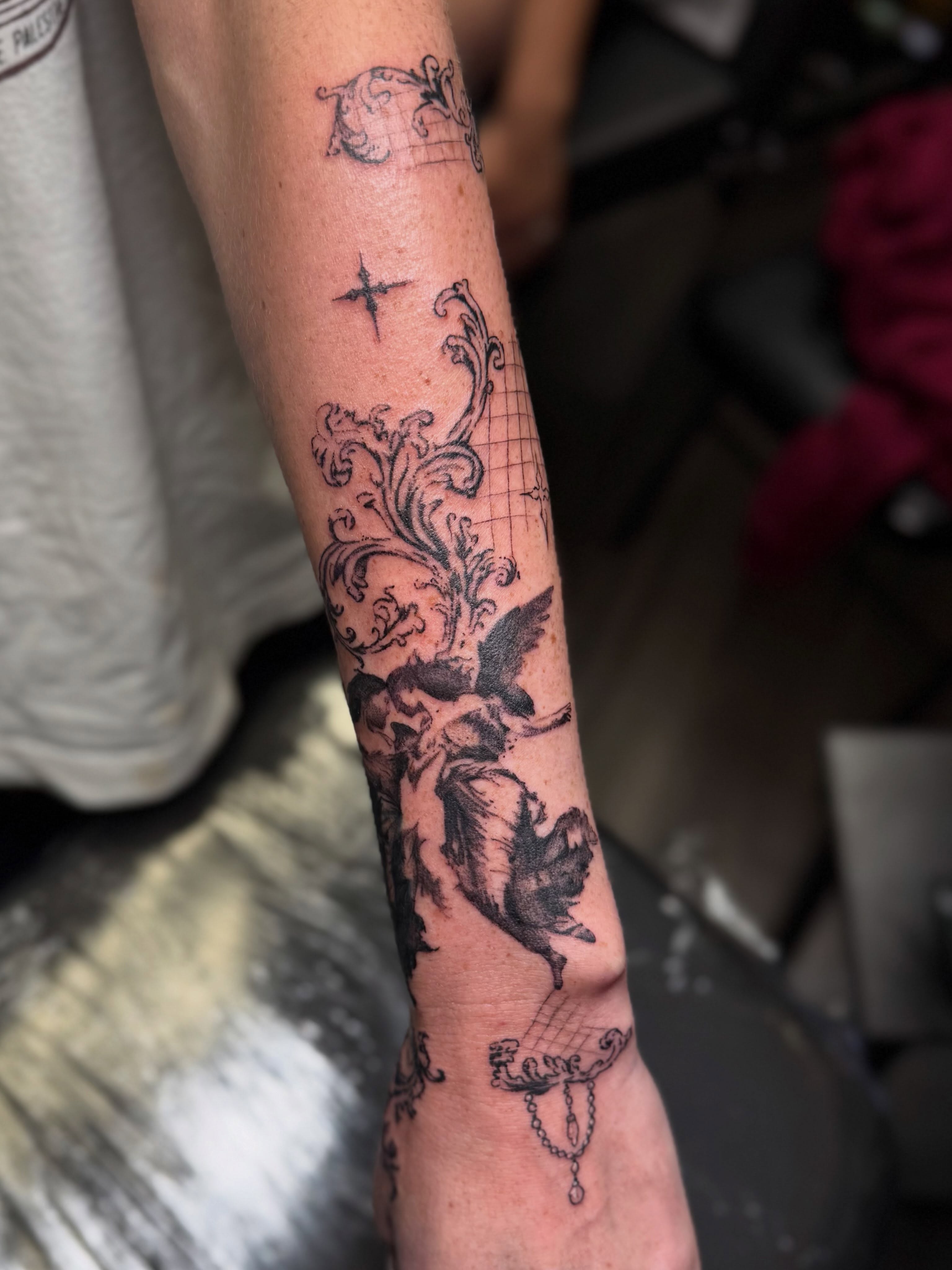 Cherub and floral neo-traditional tattoo on the forearm by βπ¬π―π’πΆ