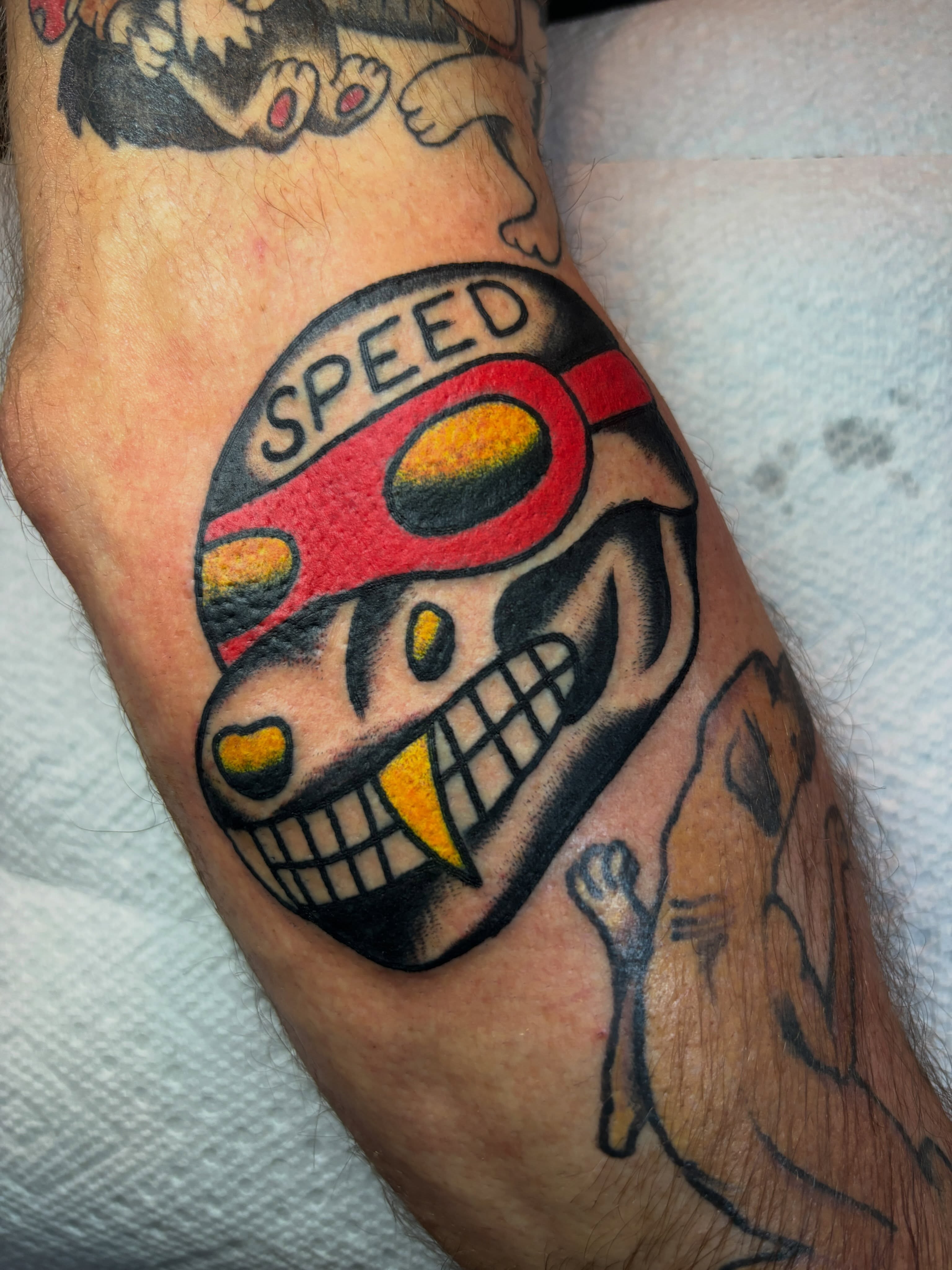 Skull with speed helmet American traditional tattoo on the forearm by Mitch Ashpaugh