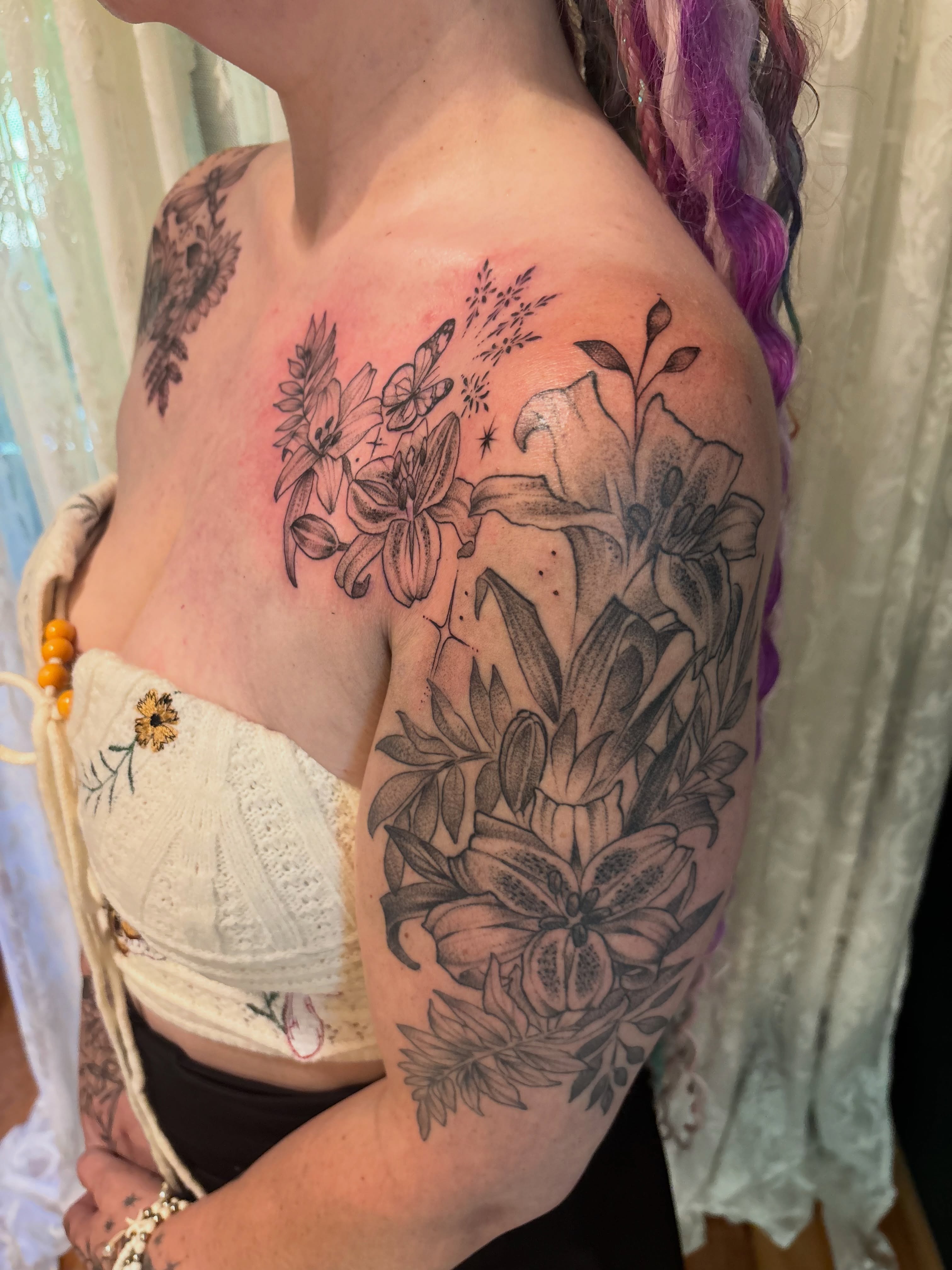 Lilies and leaves black and grey tattoo on the shoulder by Komfort Kristy