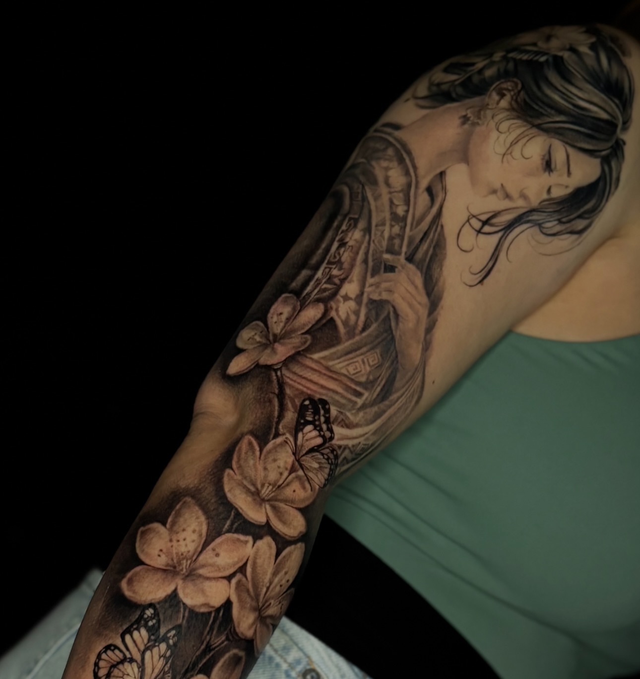 Woman with flowers and butterflies realism tattoo on the upper arm by @_frankyvee
