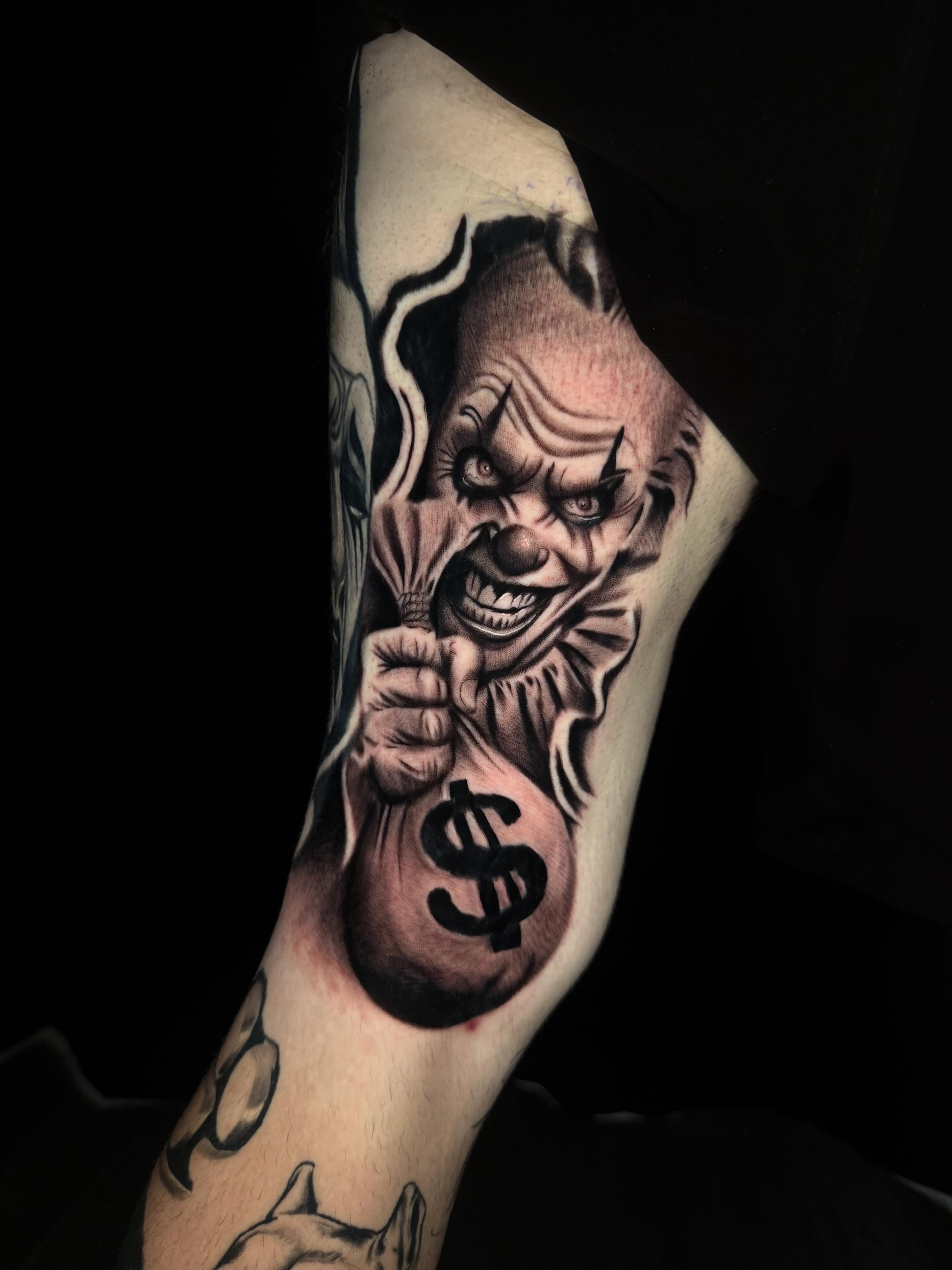Clown holding money bag realism tattoo on the forearm by Adrián Banuelos
