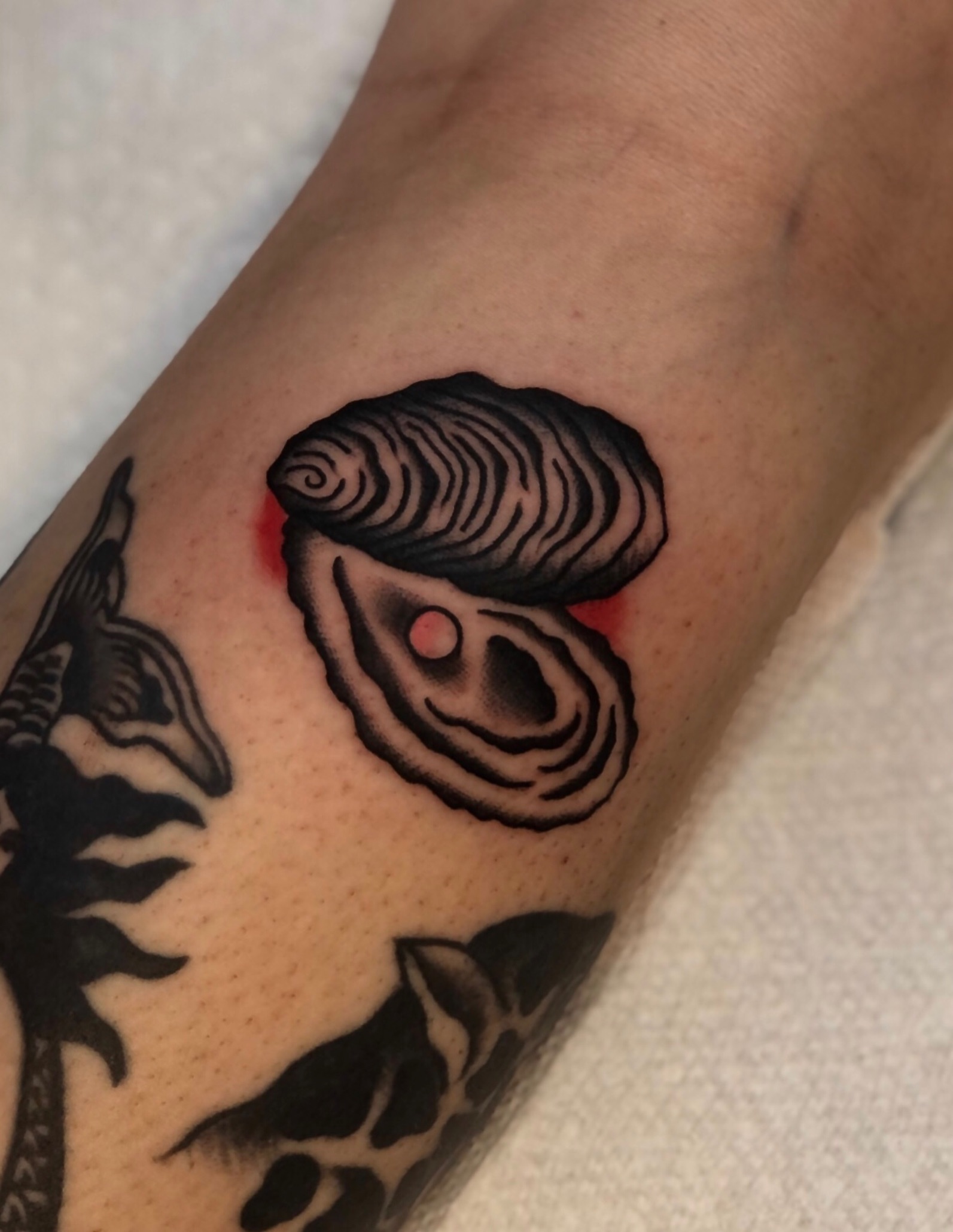 Oyster shell American traditional tattoo on the forearm by EVA Traditional Tattoos