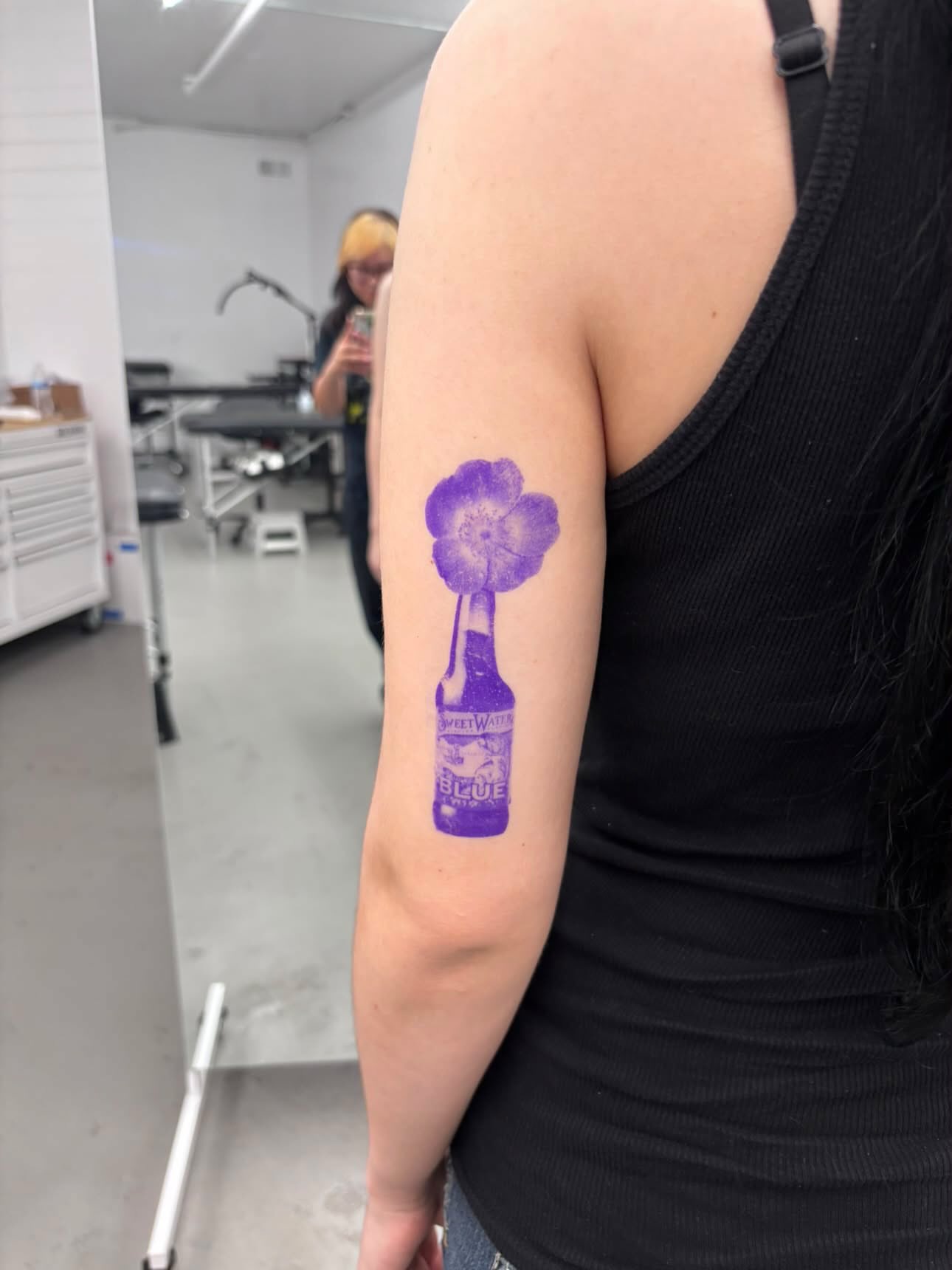 Purple beer bottle with flower dotwork tattoo on the forearm by Julianna