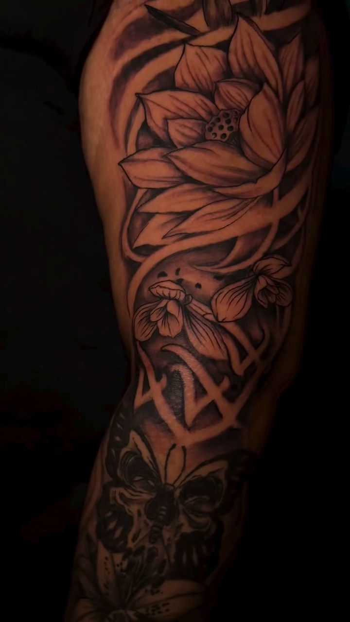 Lotus flowers, skull, and butterflies realism tattoo by Dope