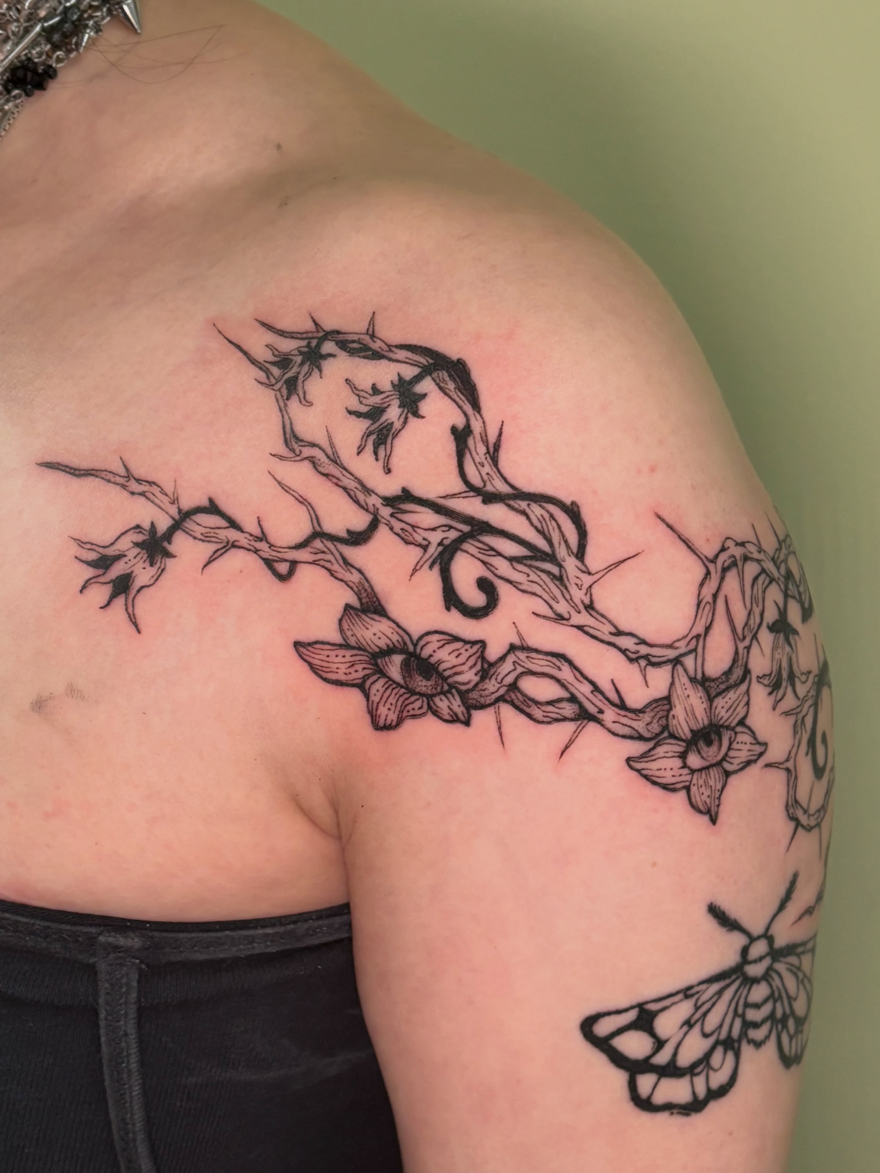 Thorn branch with flowers black and grey tattoo on the shoulder by Chloe Shay